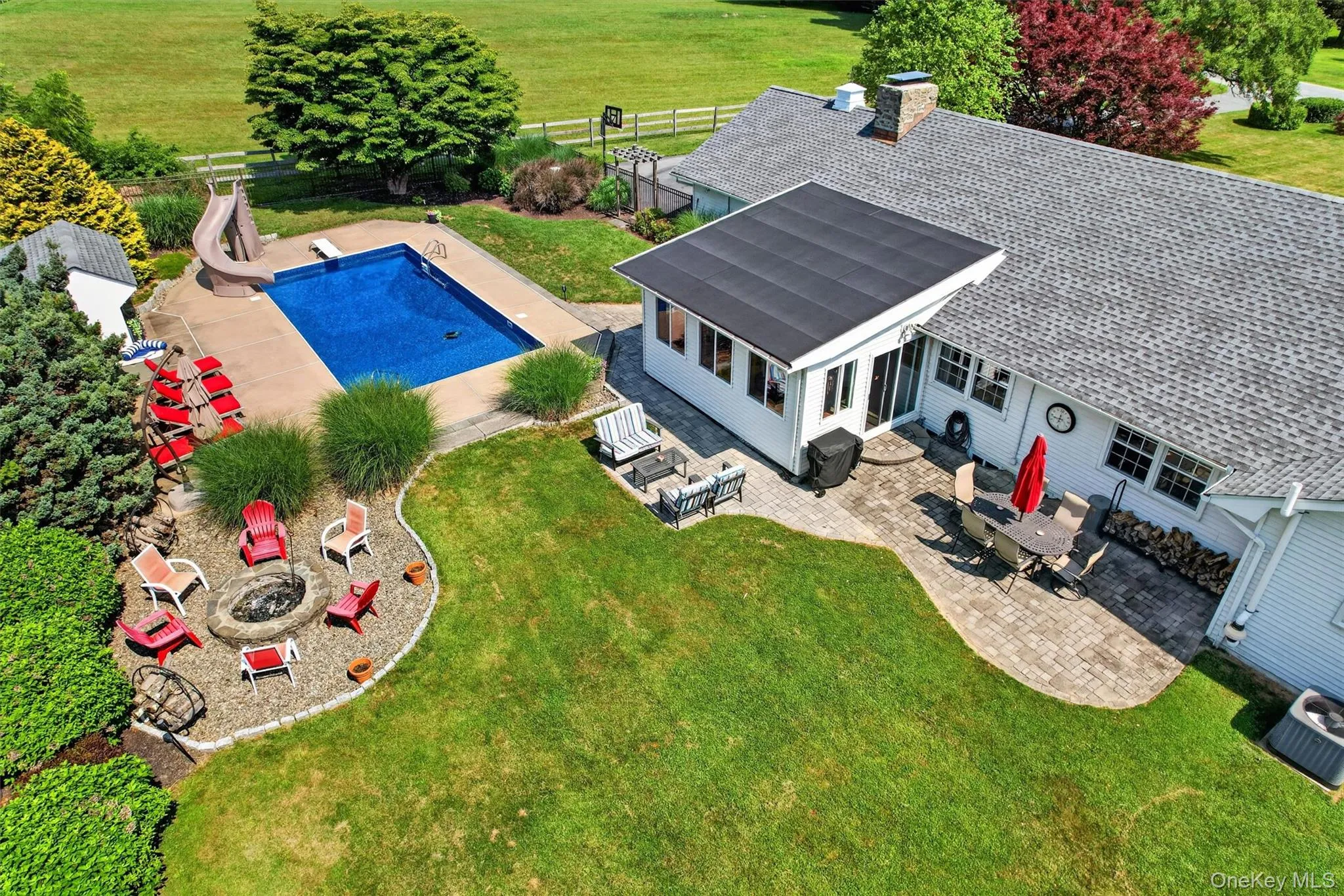 An aerial view of the backyard retreat, showcasing the inground pool with new liner, three-season sunroom, multiple patio areas, firepit, and level lawn designed for everyday enjoyment and outdoor entertaining. An incredible place to call home! An aerial view of the backyard retreat, showcasing the inground pool with new liner, three-season sunroom, multiple patio areas, firepit, and level lawn designed for everyday enjoyment and outdoor entertaining. An incredible place to call home!