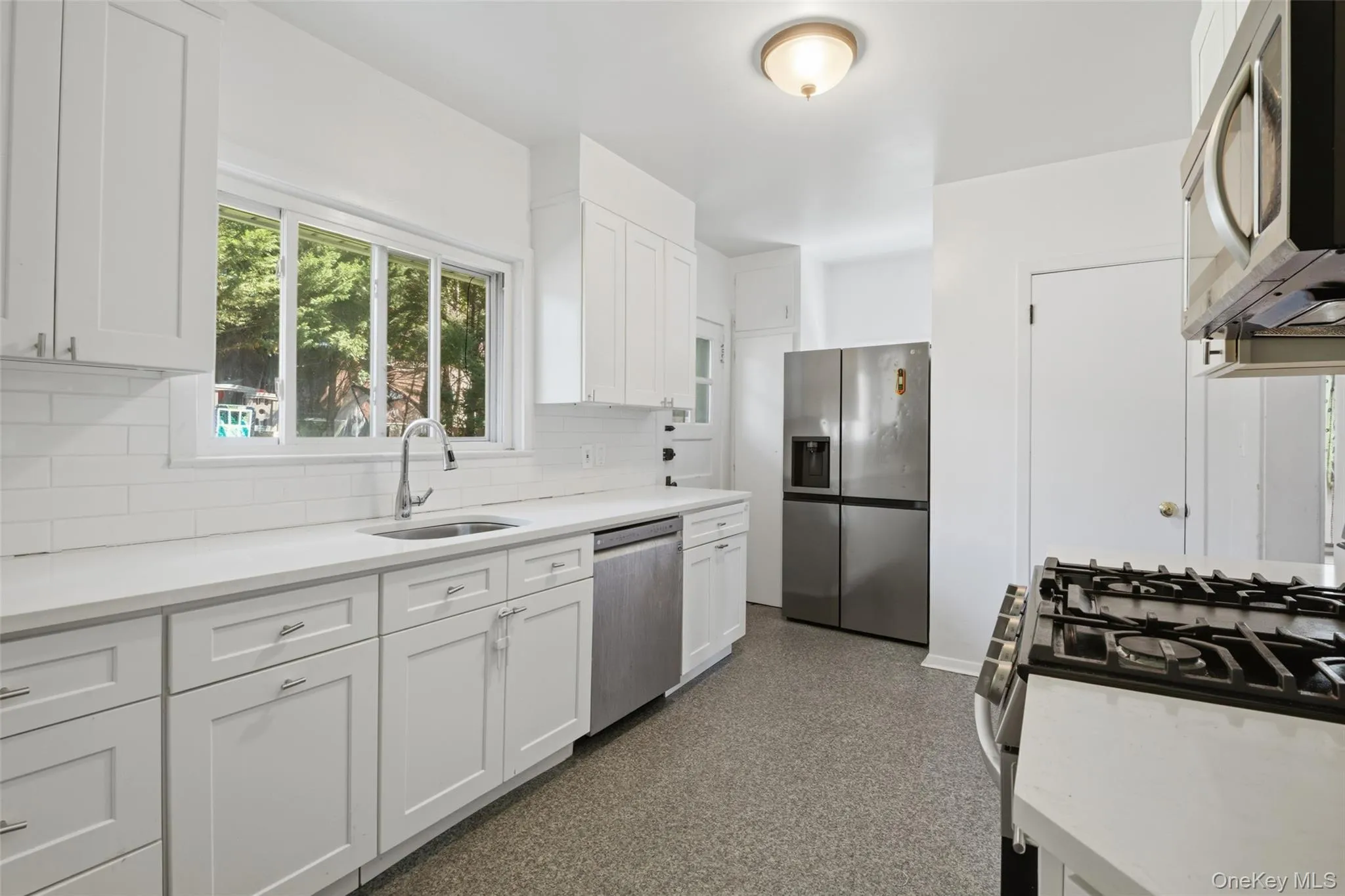 Sun-filled kitchen with modern finishes, abundant storage, and picturesque backyard views Sun-filled kitchen with modern finishes, abundant storage, and picturesque backyard views