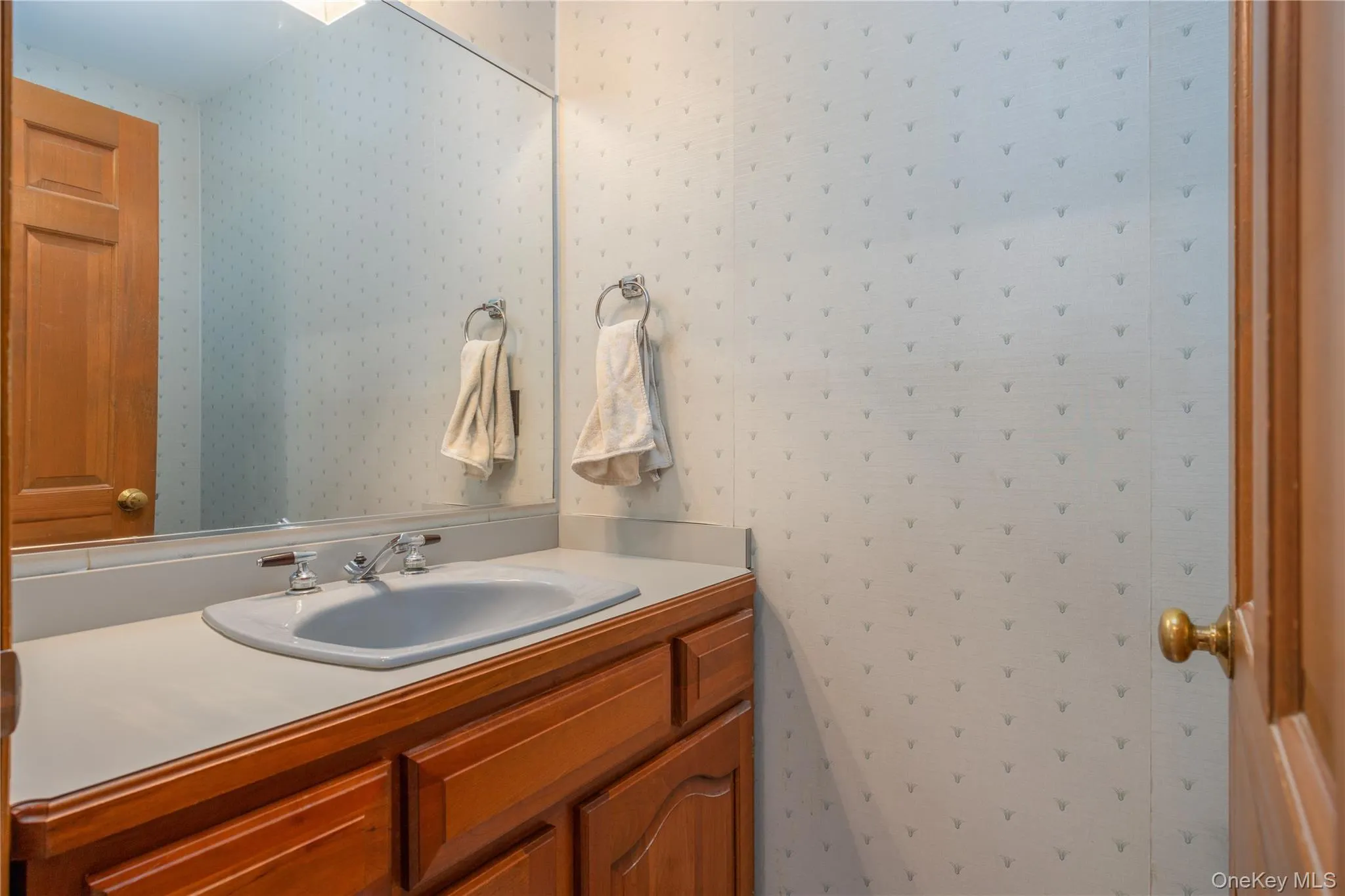 Bathroom vanity with wood cabinetry, an integrated sink, and a large wall mirror Bathroom vanity with wood cabinetry, an integrated sink, and a large wall mirror