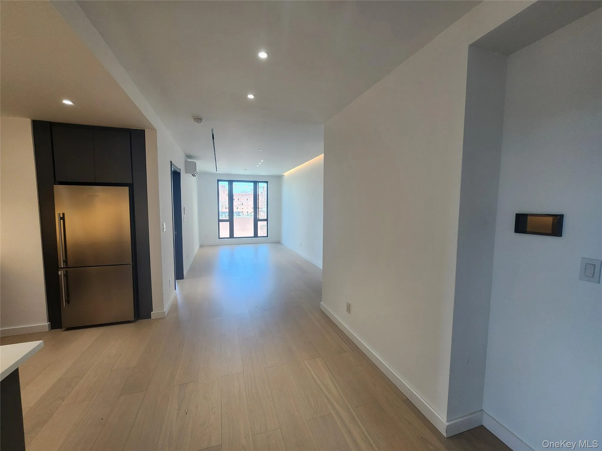 Open concept living space featuring light wood-finish flooring, recessed lighting, and a stainless steel refrigerator Open concept living space featuring light wood-finish flooring, recessed lighting, and a stainless steel refrigerator