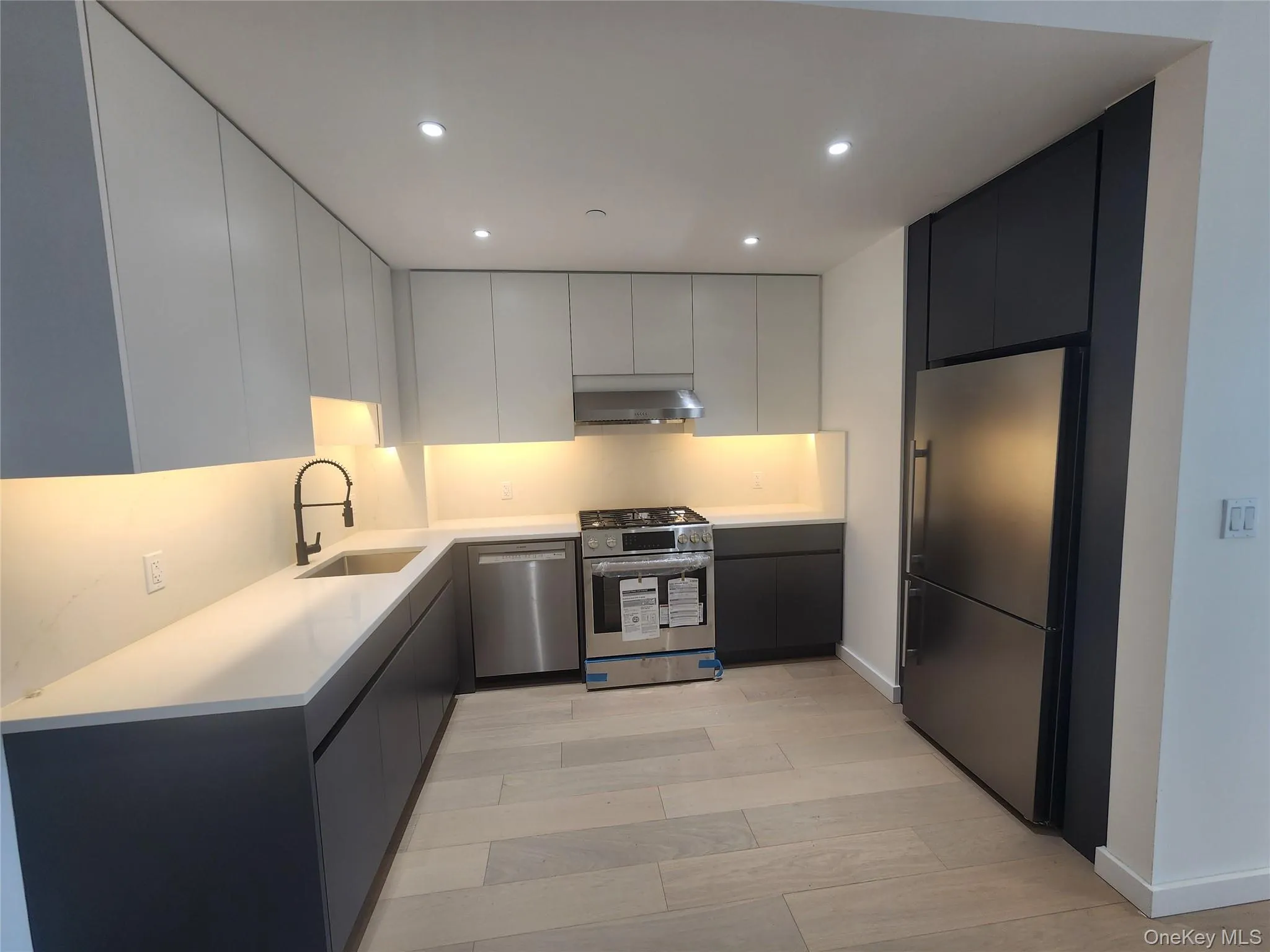 Modern kitchen featuring light wood-finish flooring and recessed ceiling lights Modern kitchen featuring light wood-finish flooring and recessed ceiling lights