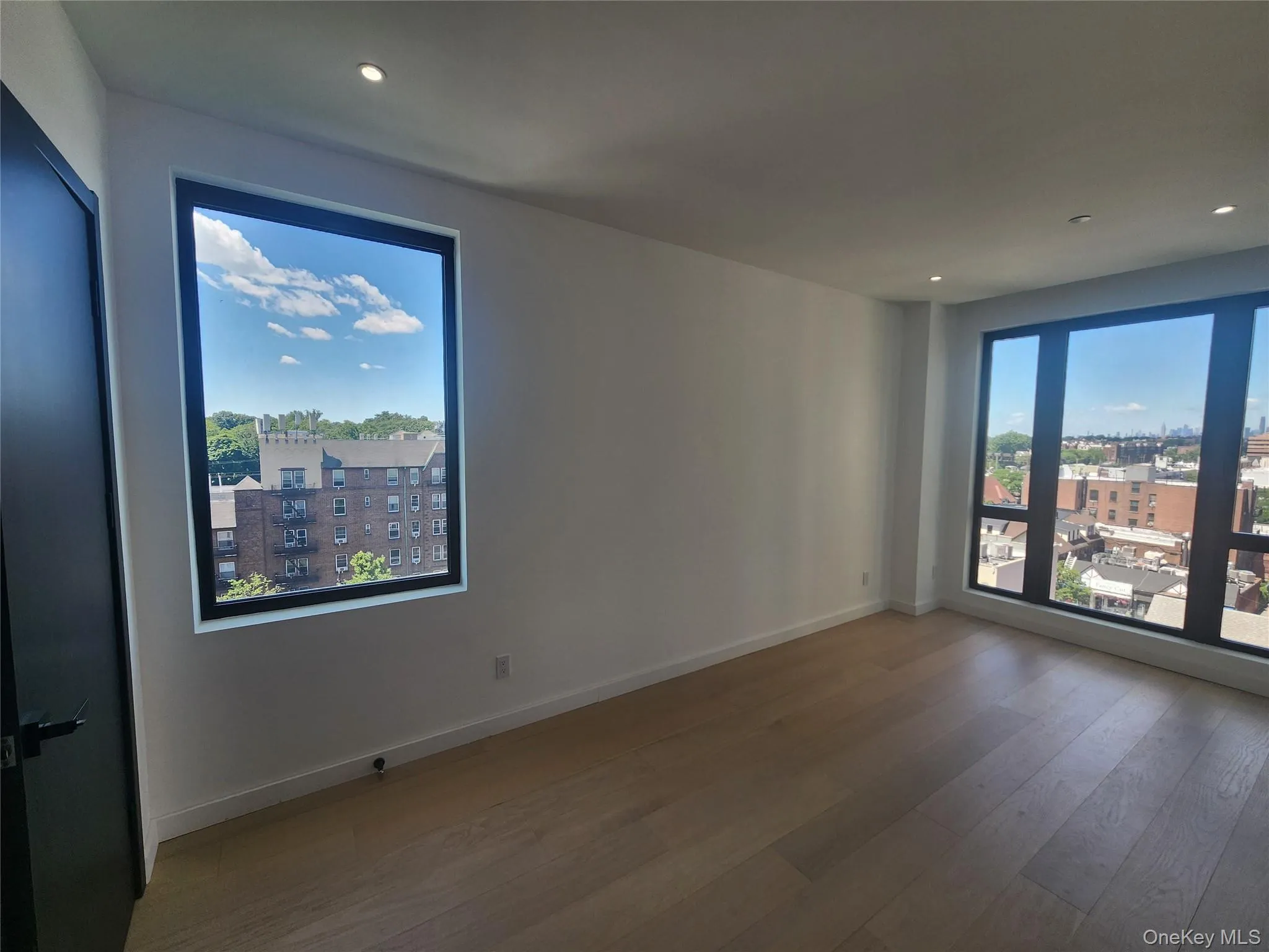 Spacious room with light wood-finish flooring, recessed lighting, and white baseboards Spacious room with light wood-finish flooring, recessed lighting, and white baseboards