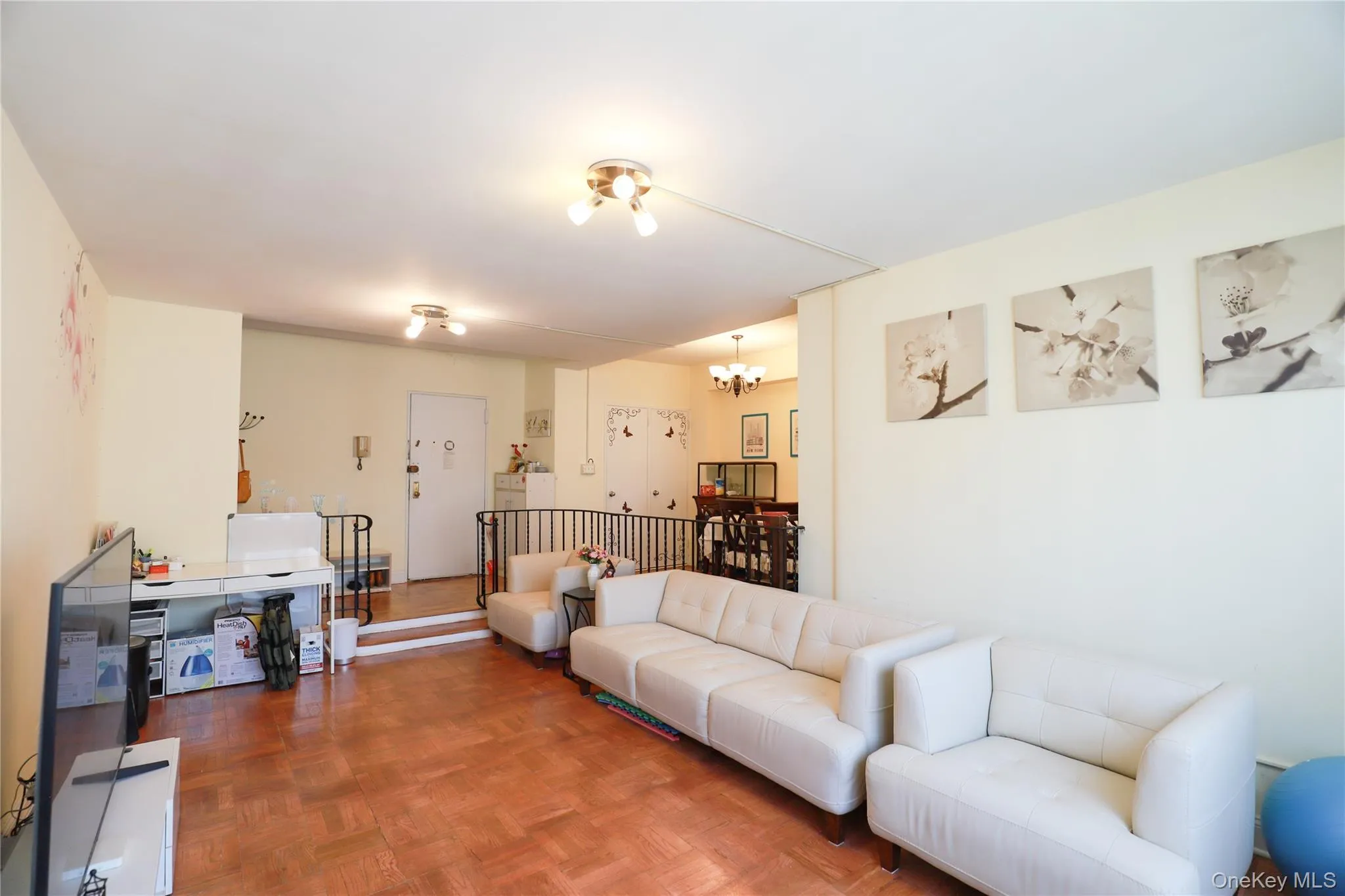 Spacious living area featuring wood-finish flooring, recessed lighting, and a defined dining space with a chandelier Spacious living area featuring wood-finish flooring, recessed lighting, and a defined dining space with a chandelier