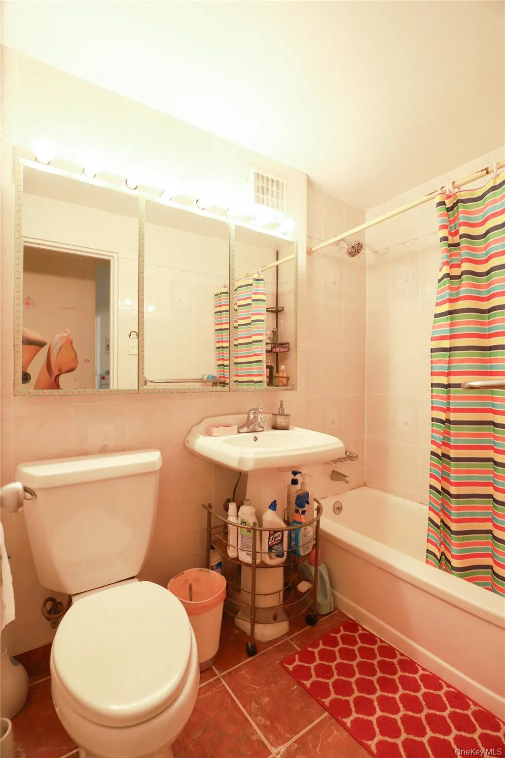 Bathroom featuring a white pedestal sink, ceramic tile flooring, and a full-size bathtub with tiled surround Bathroom featuring a white pedestal sink, ceramic tile flooring, and a full-size bathtub with tiled surround