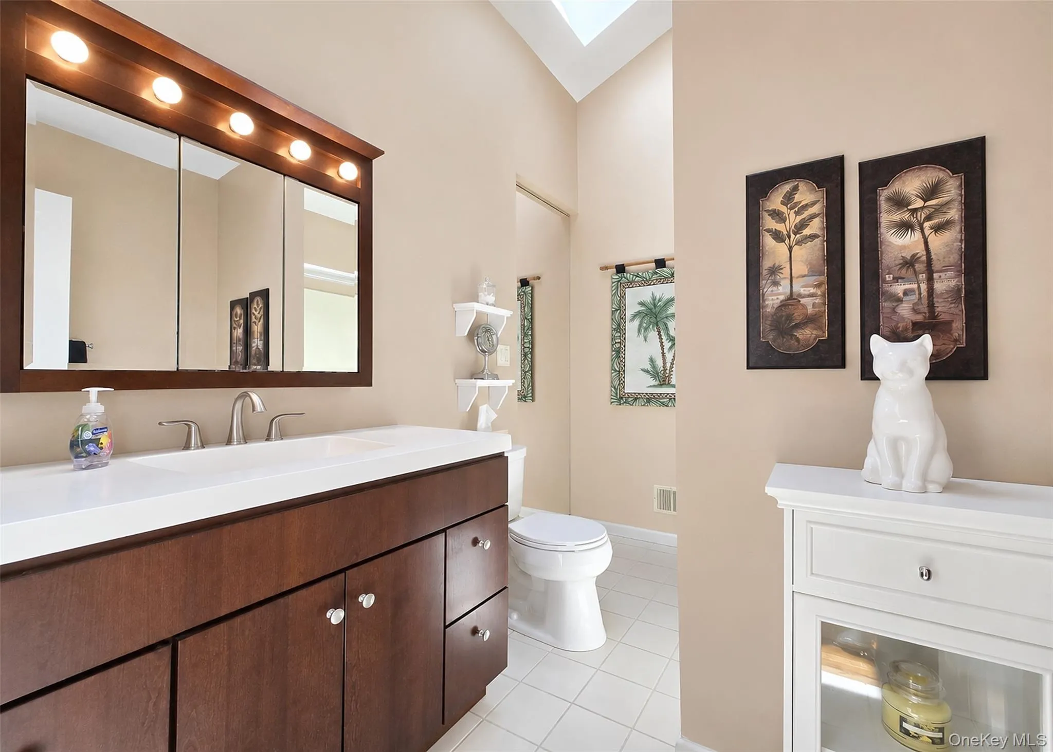 Bathroom vanity featuring a dark wood-finish cabinet with satin nickel hardware, a white countertop, and a chrome faucet Bathroom vanity featuring a dark wood-finish cabinet with satin nickel hardware, a white countertop, and a chrome faucet