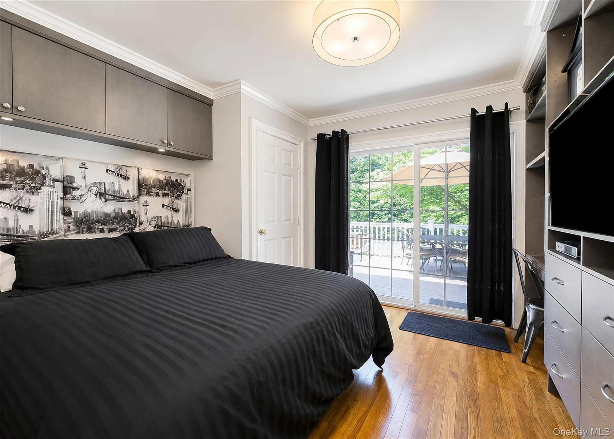 Room featuring wood-finish flooring, built-in cabinetry with task lighting, and crown molding Room featuring wood-finish flooring, built-in cabinetry with task lighting, and crown molding
