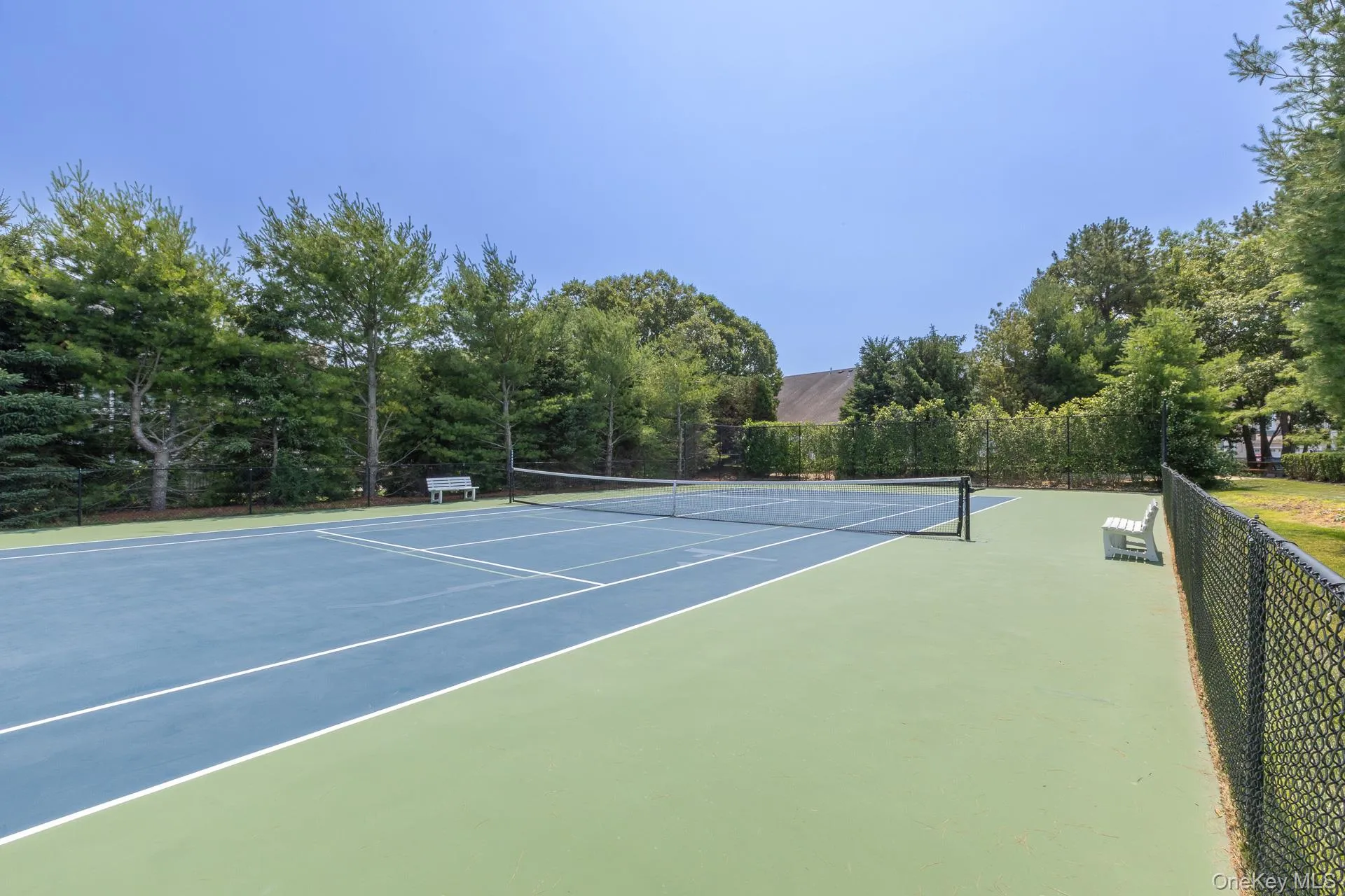 Private tennis court with regulation net and perimeter fencing Private tennis court with regulation net and perimeter fencing