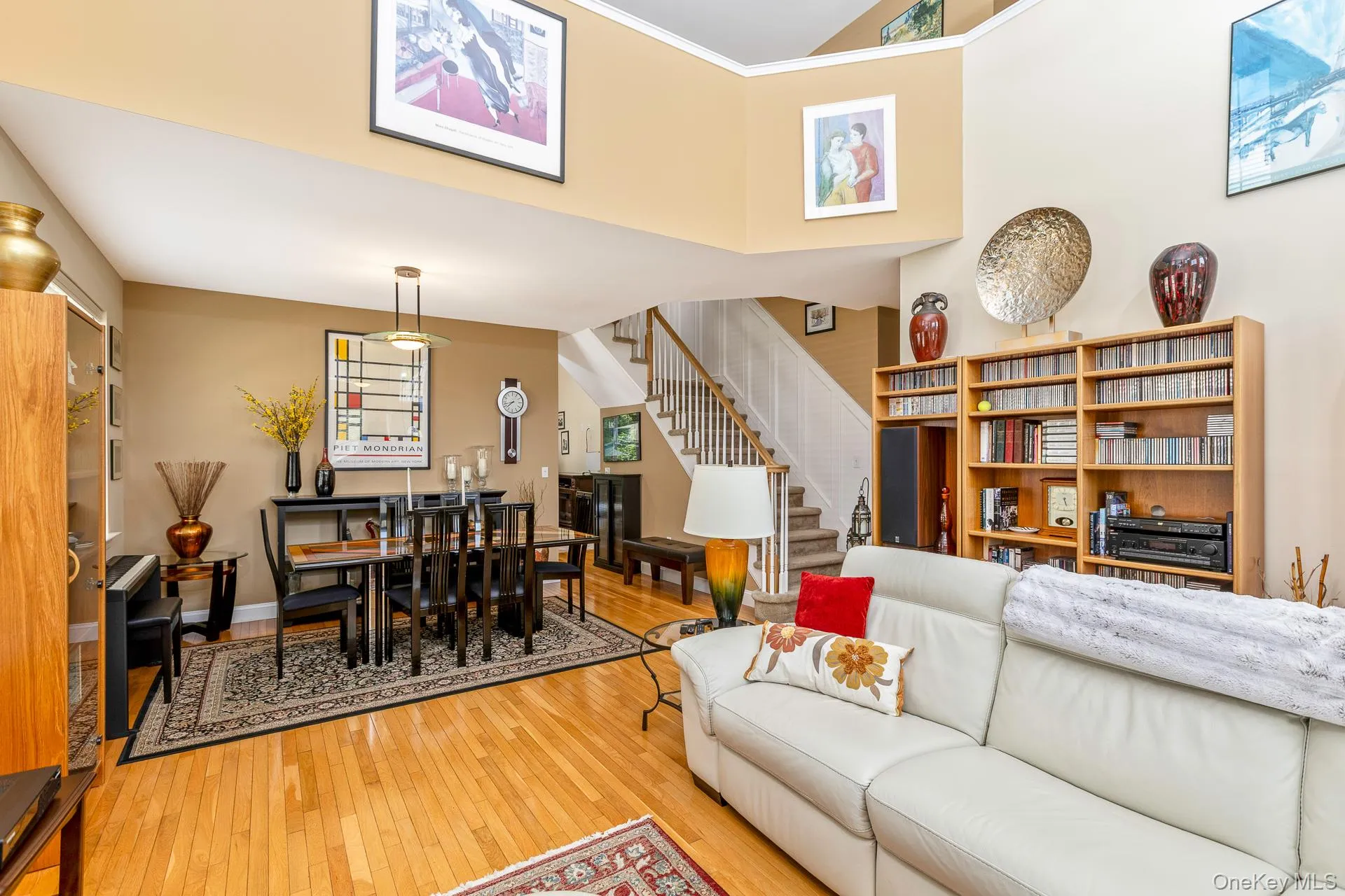 Open-concept living area featuring a two-story ceiling, and a staircase with white risers and wood treads Open-concept living area featuring a two-story ceiling, and a staircase with white risers and wood treads