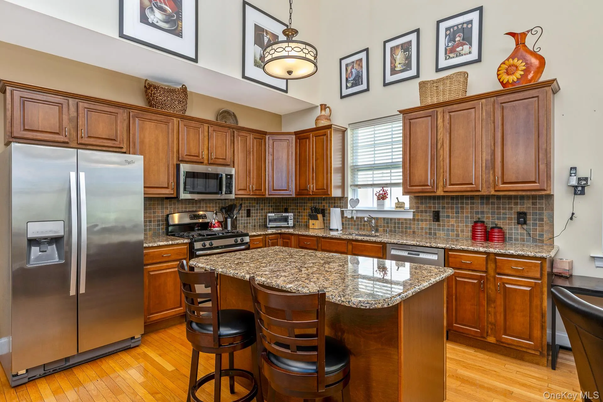 Kitchen featuring a central island with a granite countertop, wood cabinetry, stainless steel appliances Kitchen featuring a central island with a granite countertop, wood cabinetry, stainless steel appliances