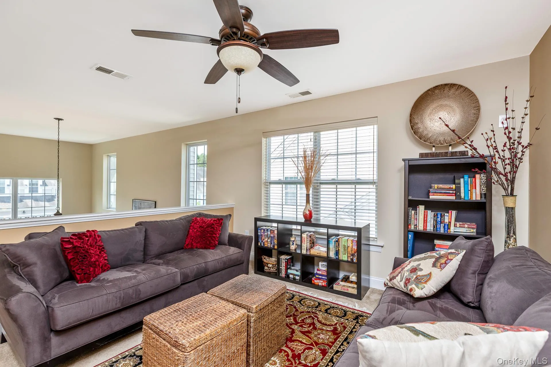 Living area featuring a ceiling fan with integrated lighting, multiple windows with blinds, and a partial wall separating spaces Living area featuring a ceiling fan with integrated lighting, multiple windows with blinds, and a partial wall separating spaces