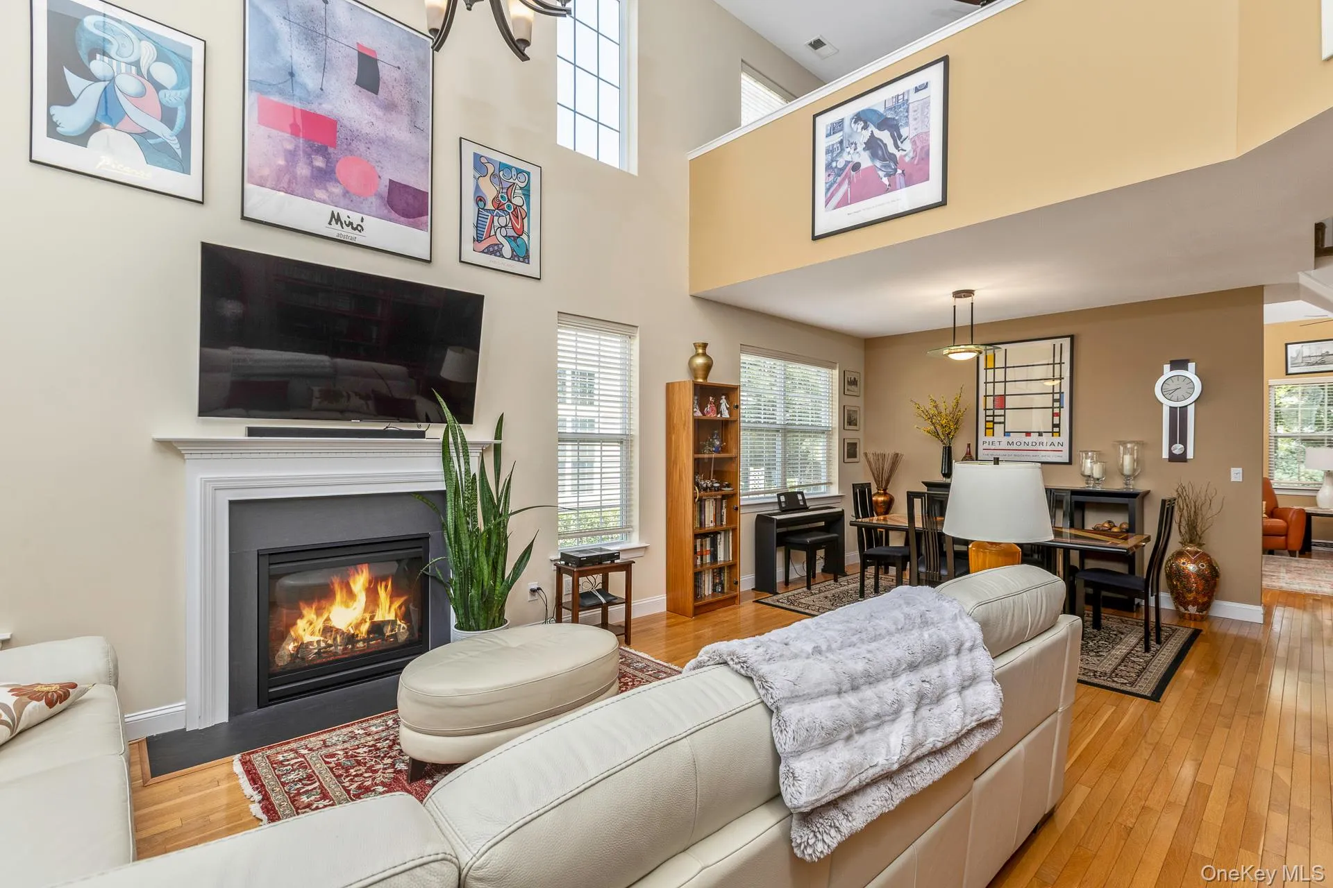Open-concept living space featuring a fireplace, a dining area, and a lofted upper level with an overlook Open-concept living space featuring a fireplace, a dining area, and a lofted upper level with an overlook