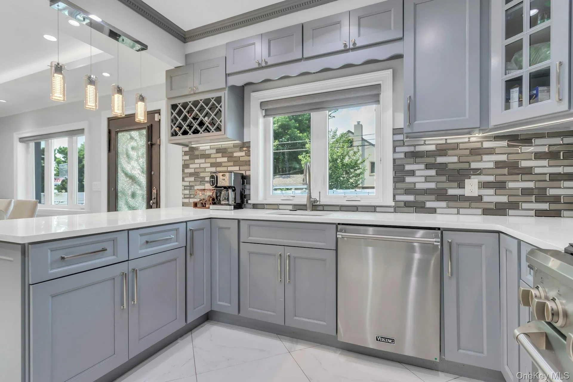 Contemporary kitchen featuring light gray cabinetry, white quartz countertops, undermount lighting, coutner seating Contemporary kitchen featuring light gray cabinetry, white quartz countertops, undermount lighting, coutner seating