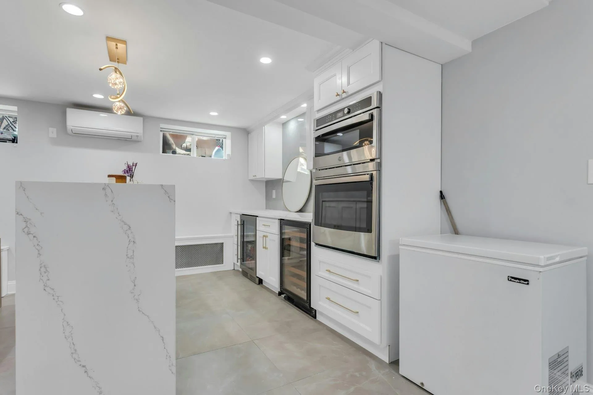 Bonus: Contemporary kitchen space featuring a waterfall island with veined quartz, recessed lighting, and a gold-tone linear chandelier Bonus: Contemporary kitchen space featuring a waterfall island with veined quartz, recessed lighting, and a gold-tone linear chandelier