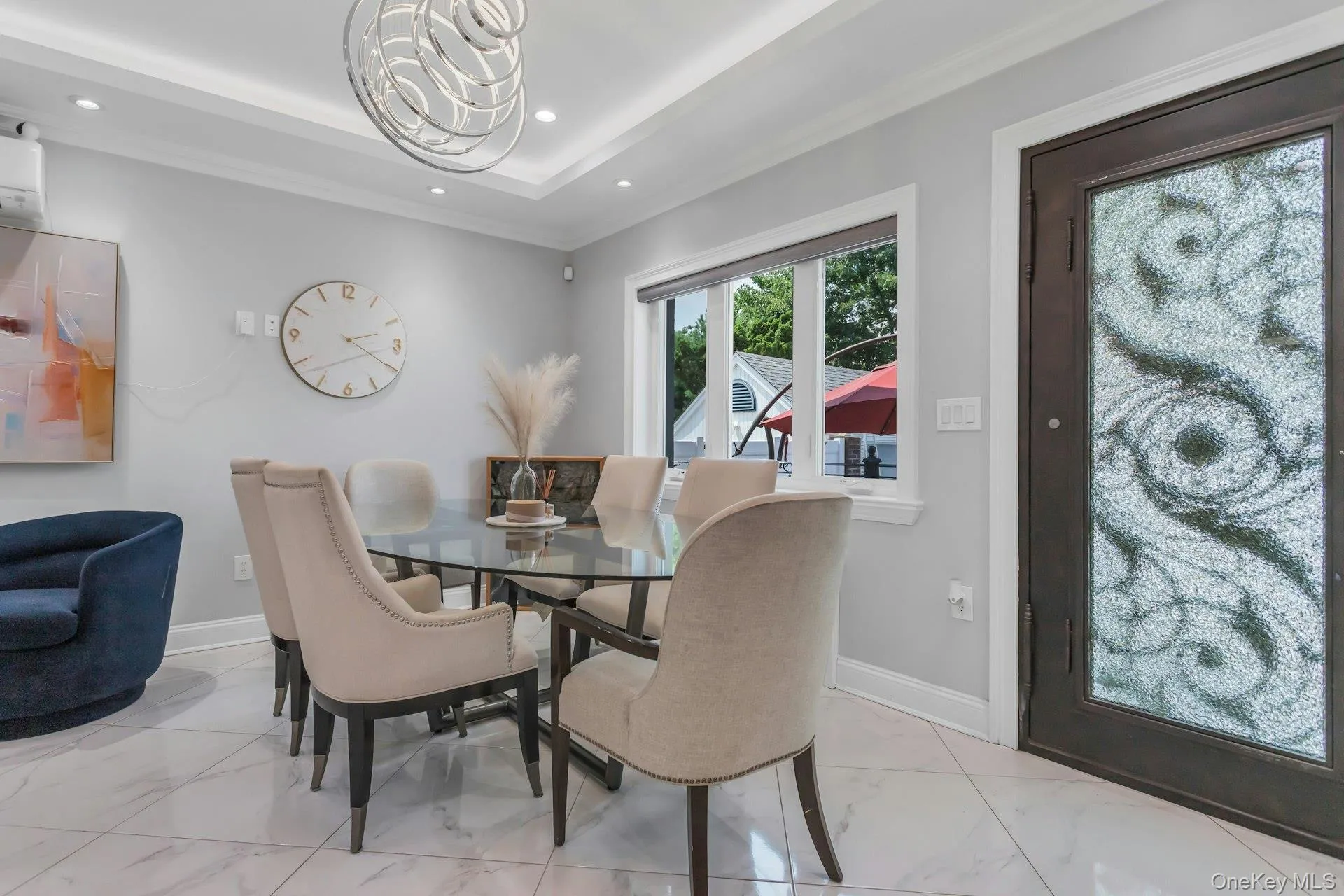 Dining area featuring a contemporary chandelier, recessed lighting, crown molding, white tile flooring, and a decorative glass iron entry door Dining area featuring a contemporary chandelier, recessed lighting, crown molding, white tile flooring, and a decorative glass iron entry door