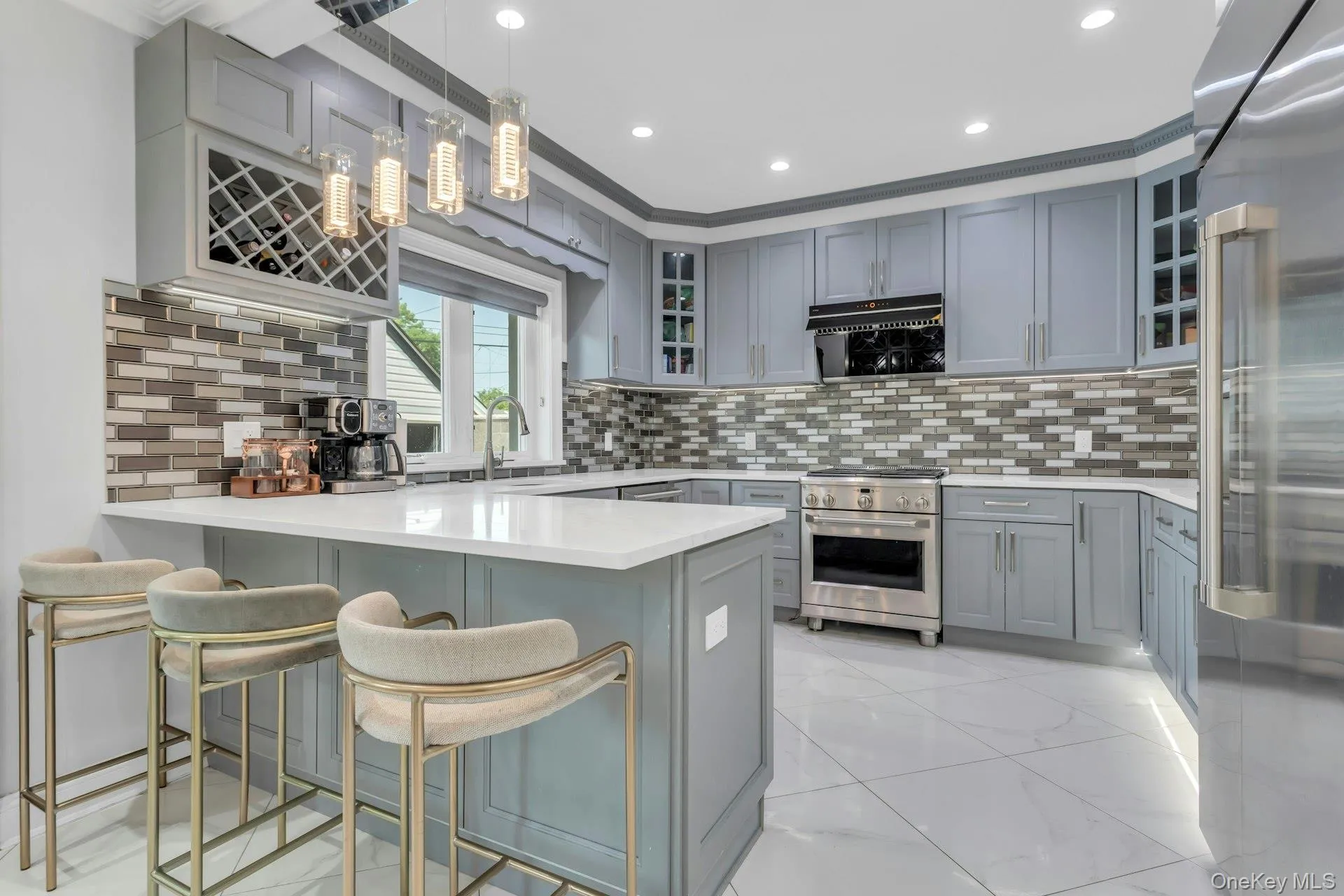 Custom cabinetry with integrated wine rack, stainless steel top of the line appliances, white quartz countertops, over-sized porcelain tile flooring, and a glass subway tile backsplash Custom cabinetry with integrated wine rack, stainless steel top of the line appliances, white quartz countertops, over-sized porcelain tile flooring, and a glass subway tile backsplash