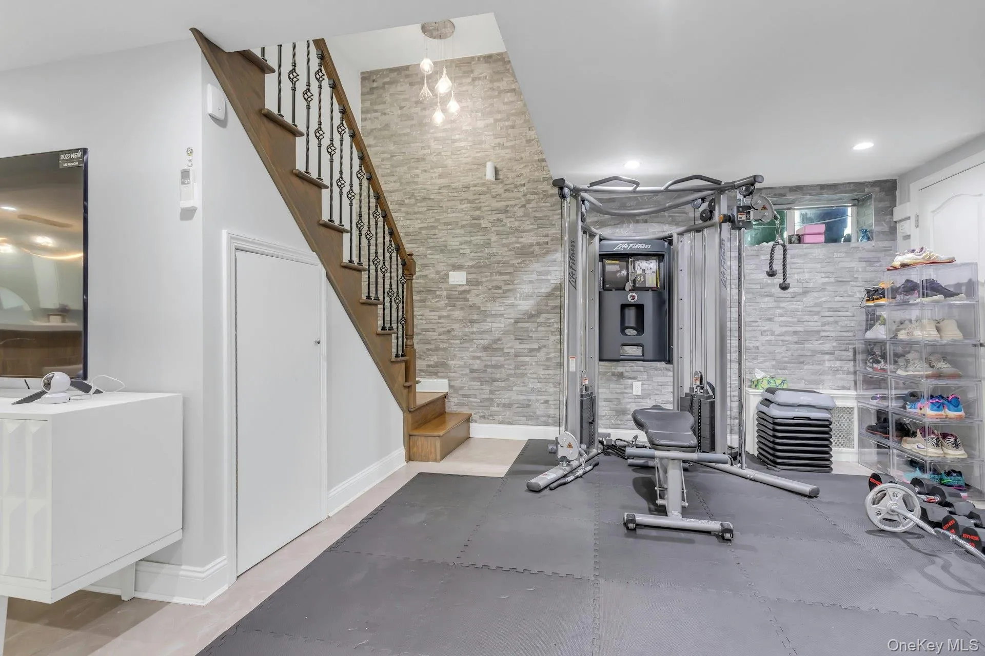 Finished lower level featuring a full staircase with wood treads and decorative iron balusters, stone accent walls, recessed lighting with lots of storage Finished lower level featuring a full staircase with wood treads and decorative iron balusters, stone accent walls, recessed lighting with lots of storage