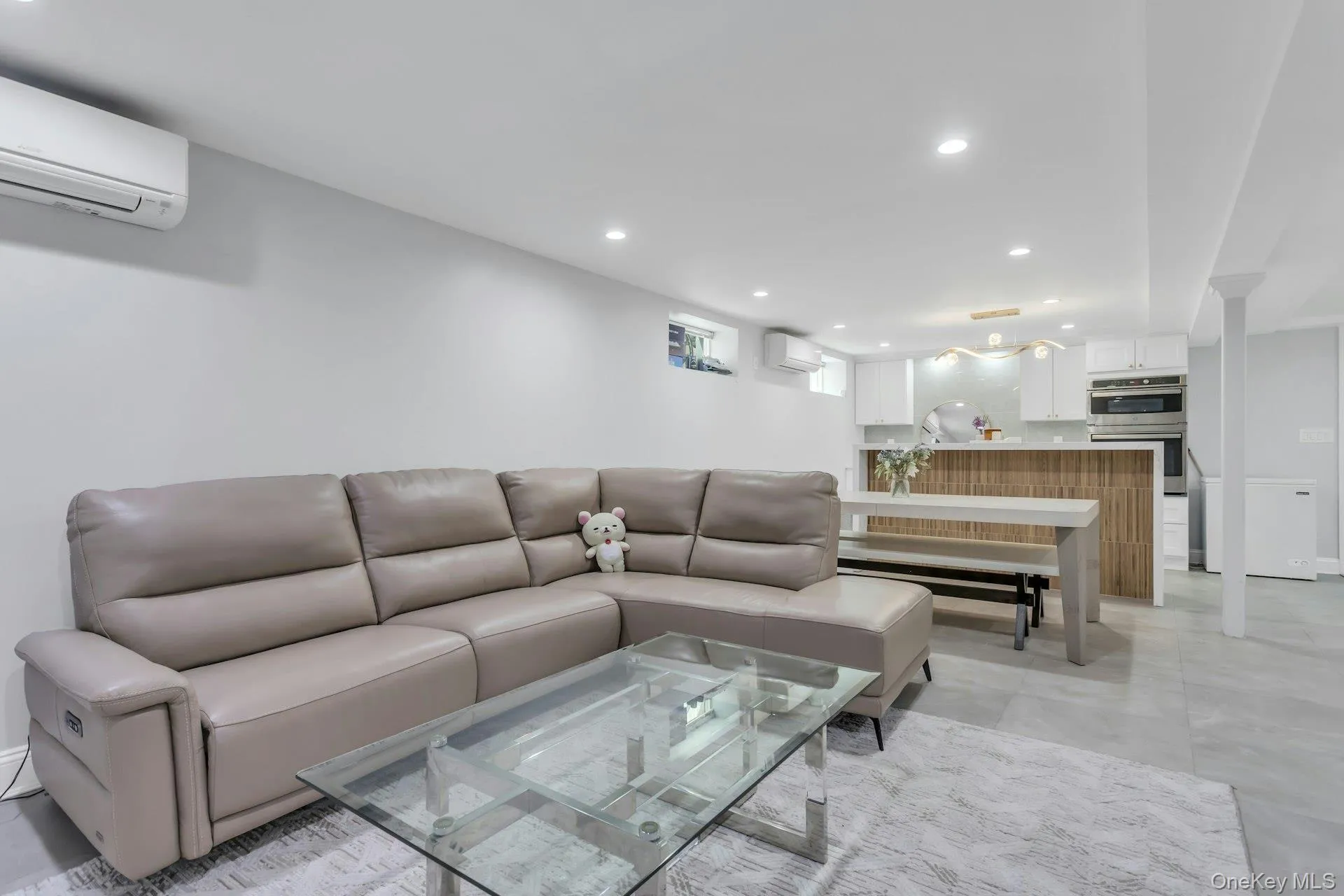 Lower level Open-concept living area featuring light gray walls, recessed lighting, and large format tile flooring Lower level Open-concept living area featuring light gray walls, recessed lighting, and large format tile flooring