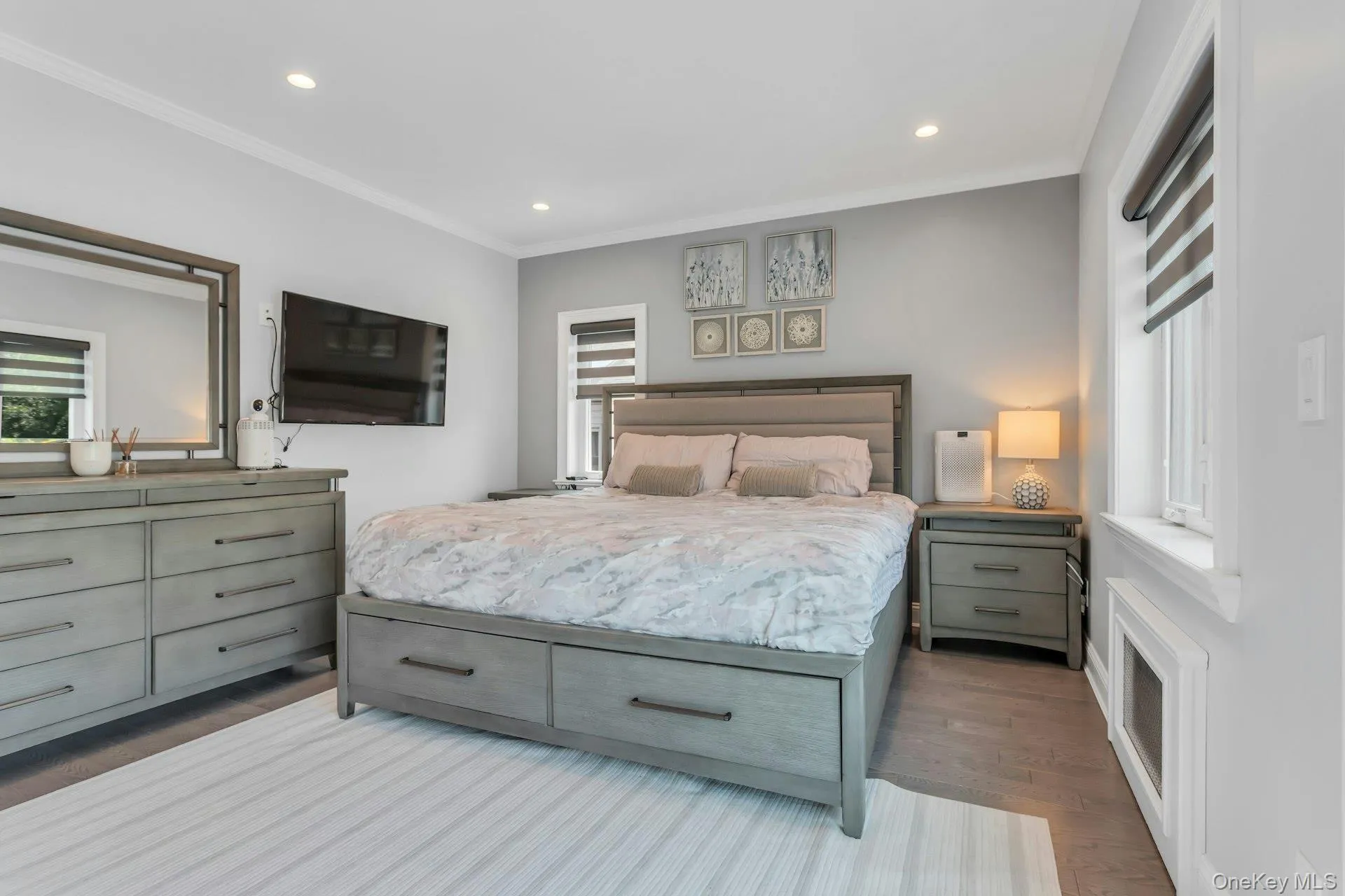 Bedroom featuring wood-finish flooring, recessed lighting, crown molding, and two windows with electric blinds Bedroom featuring wood-finish flooring, recessed lighting, crown molding, and two windows with electric blinds