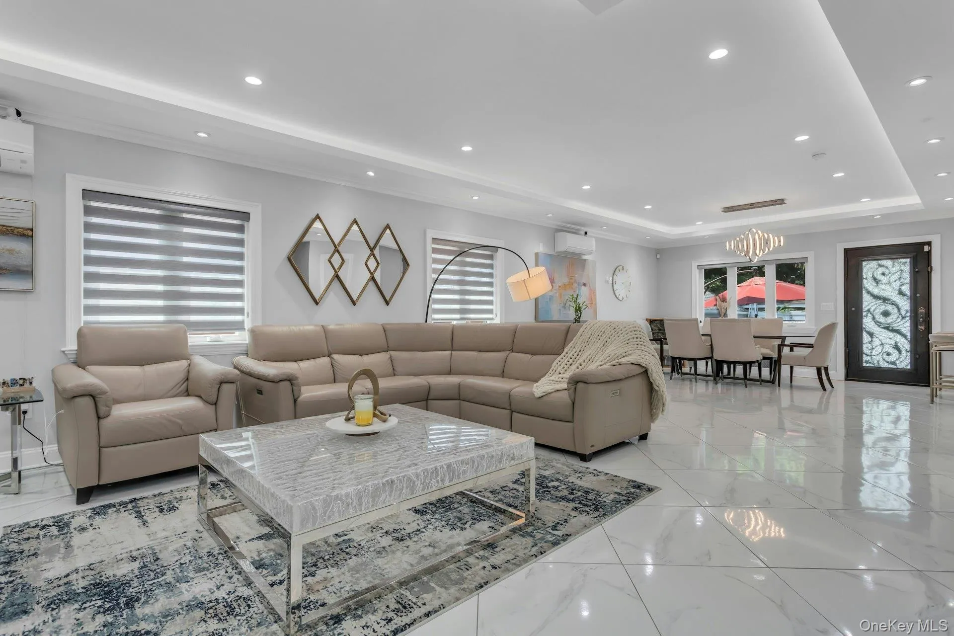 Expansive open concept living area featuring large polished tile flooring, recessed, and cove ceiling lighting, and ceiling crown and floor molding Expansive open concept living area featuring large polished tile flooring, recessed, and cove ceiling lighting, and ceiling crown and floor molding