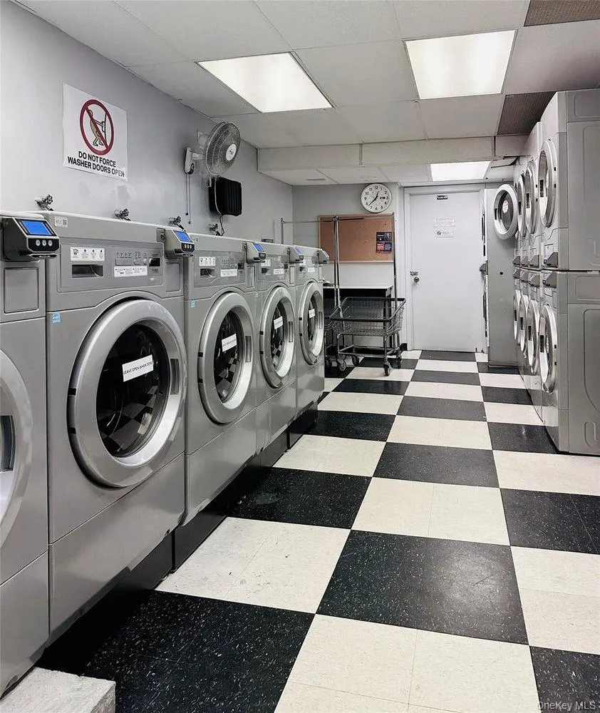 Dedicated laundry room featuring multiple front-loading washing machines and top-loading dryers Dedicated laundry room featuring multiple front-loading washing machines and top-loading dryers