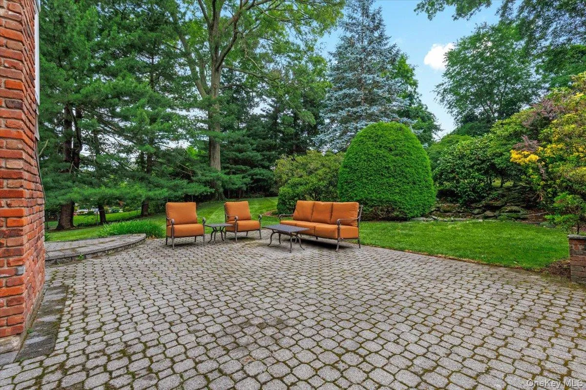 Large patio featuring a stone border and a verdant landscape with mature trees Large patio featuring a stone border and a verdant landscape with mature trees