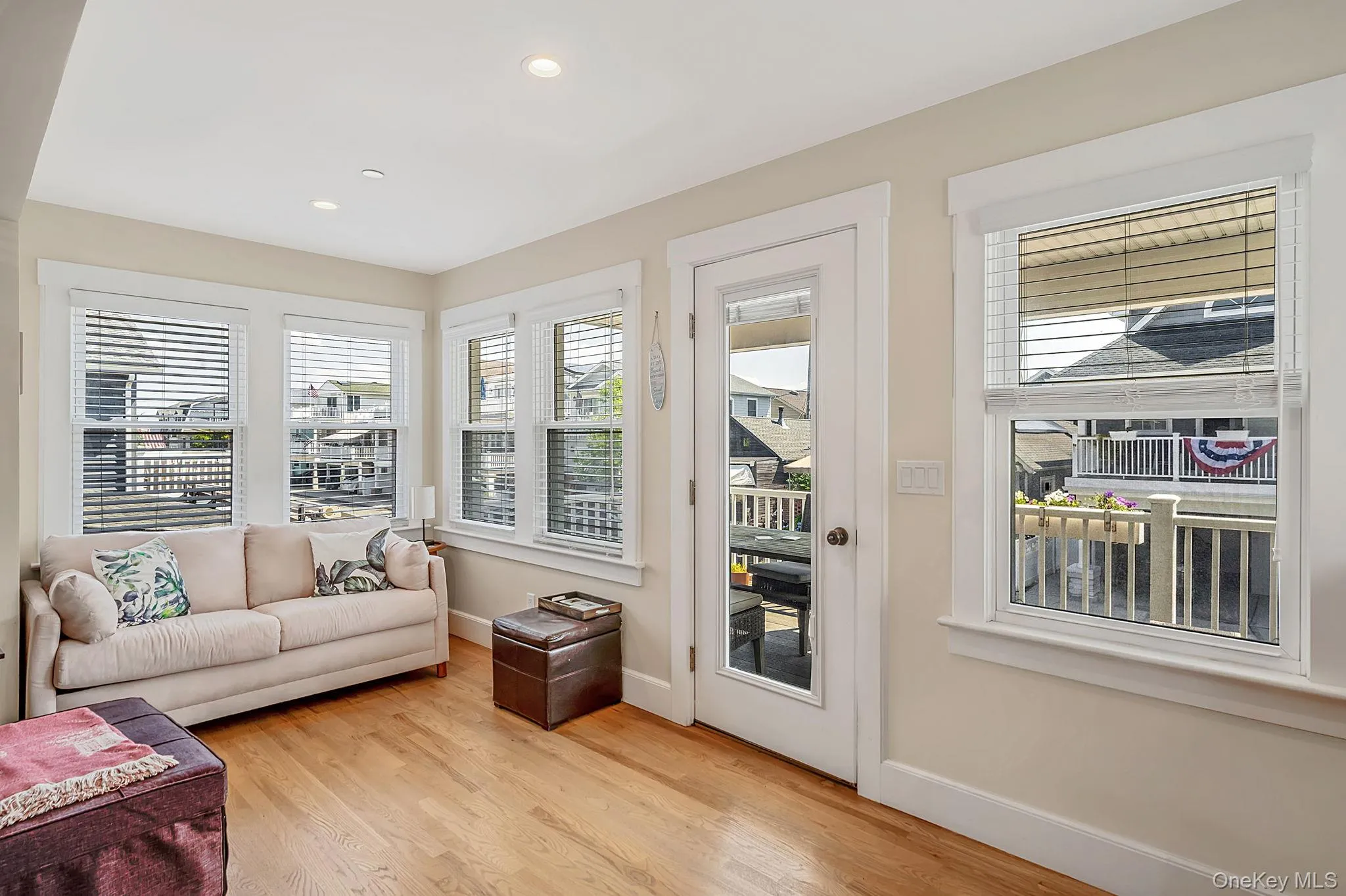 Bright, sun-filled living room with hardwood floors and access to second level covered deck Bright, sun-filled living room with hardwood floors and access to second level covered deck