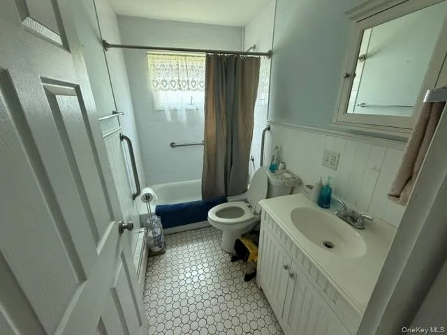 Bathroom featuring a white vanity with integrated sink, white hexagonal tile flooring, and a window for natural light Bathroom featuring a white vanity with integrated sink, white hexagonal tile flooring, and a window for natural light