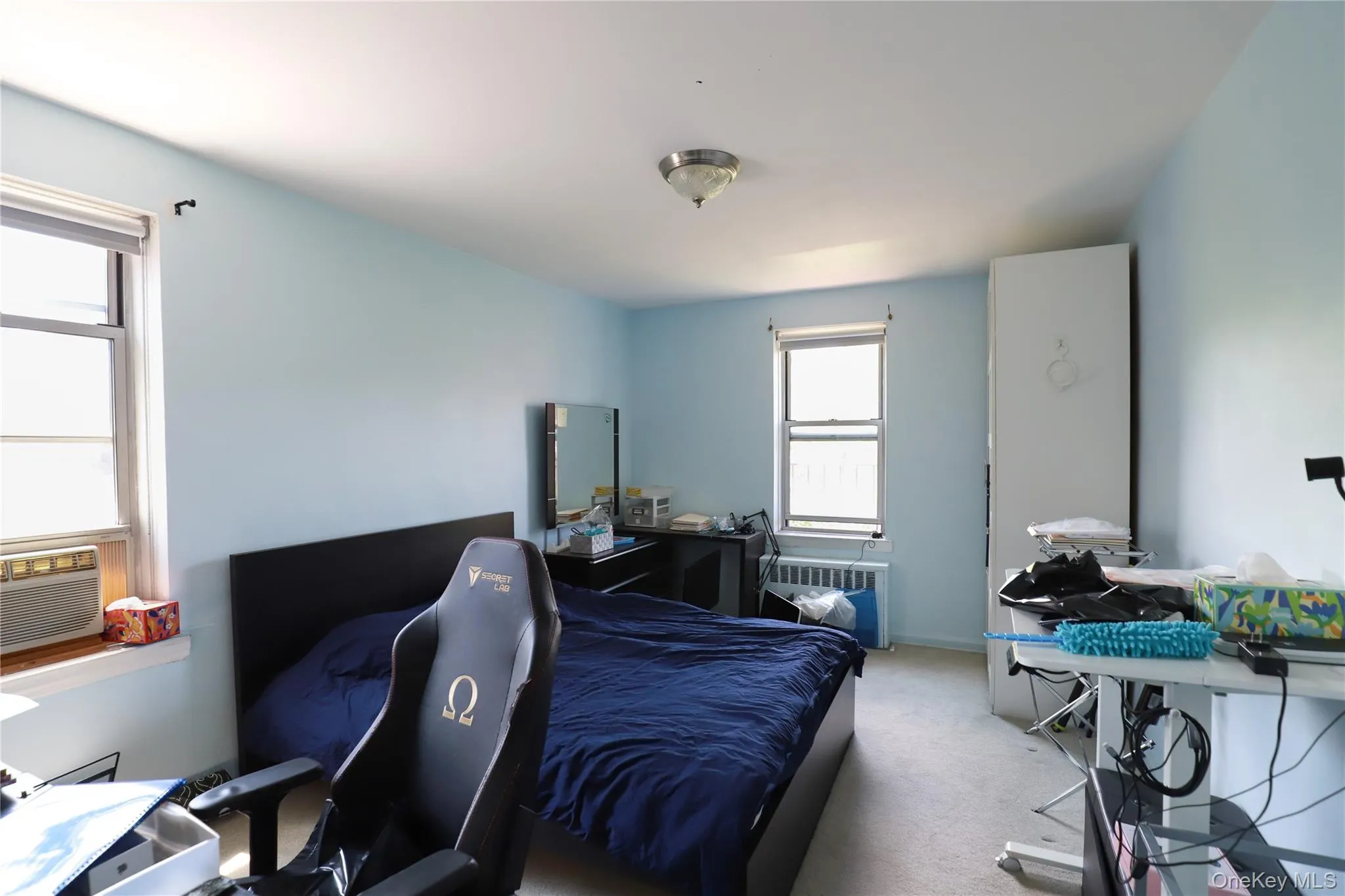 Spacious bedroom featuring two windows, light blue walls, and wall-to-wall carpeting Spacious bedroom featuring two windows, light blue walls, and wall-to-wall carpeting