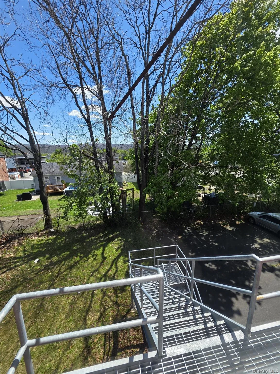 Exterior metal staircase with handrails providing access to an asphalt parking area Exterior metal staircase with handrails providing access to an asphalt parking area