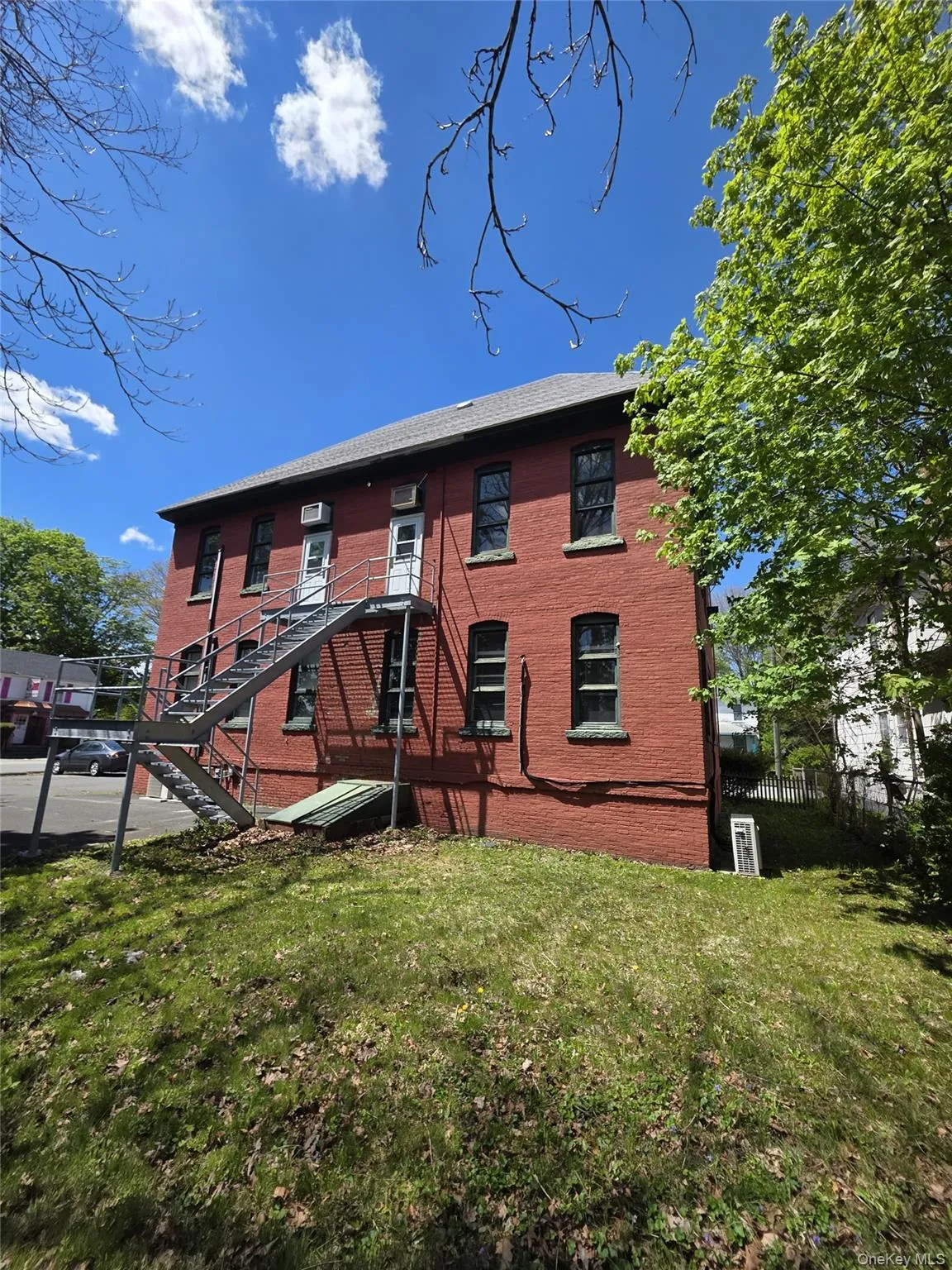 Red brick exterior with multiple windows and a gray pitched roof Red brick exterior with multiple windows and a gray pitched roof