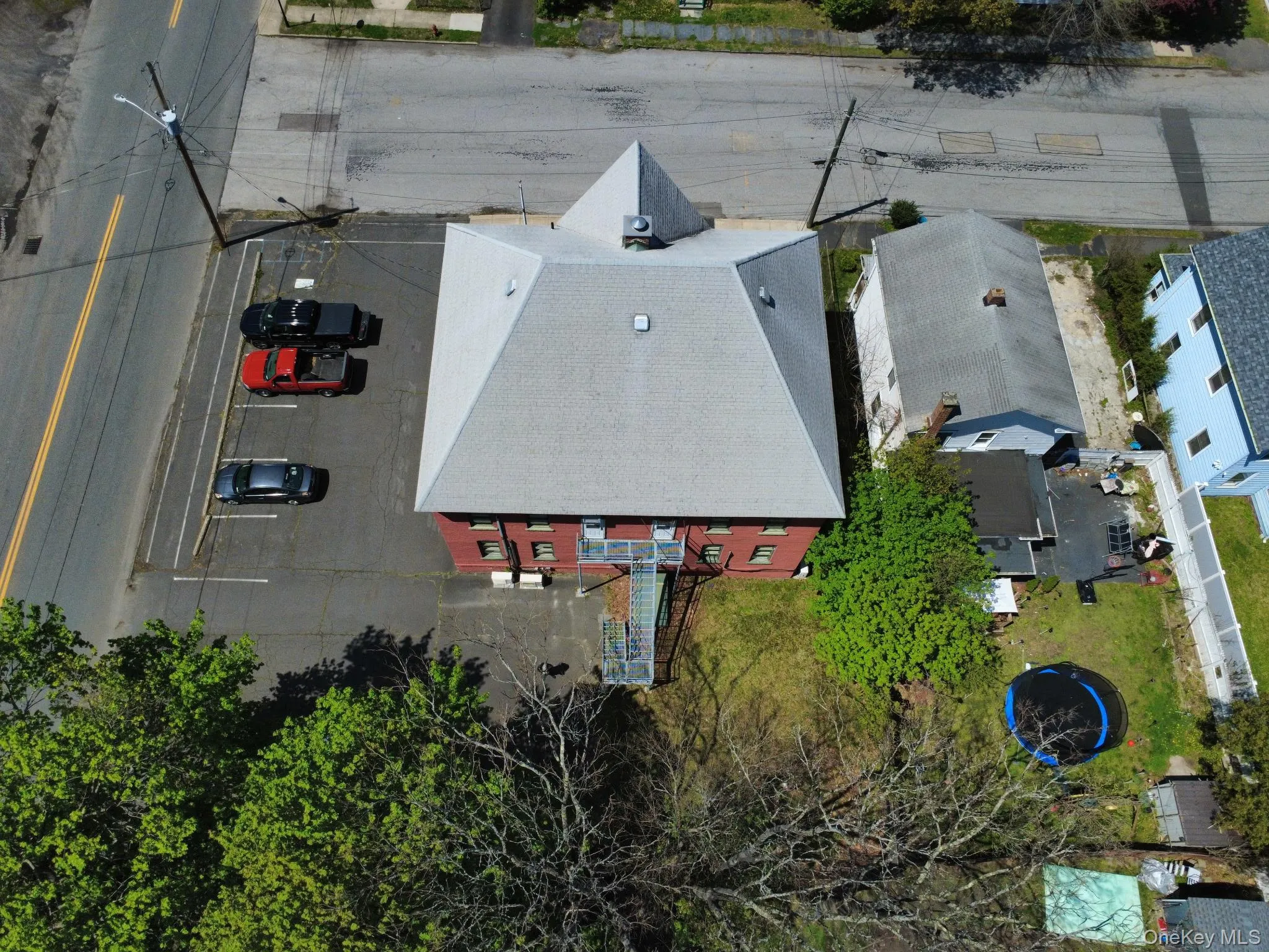 Red brick building with a gray hip roof and multiple window openings Red brick building with a gray hip roof and multiple window openings