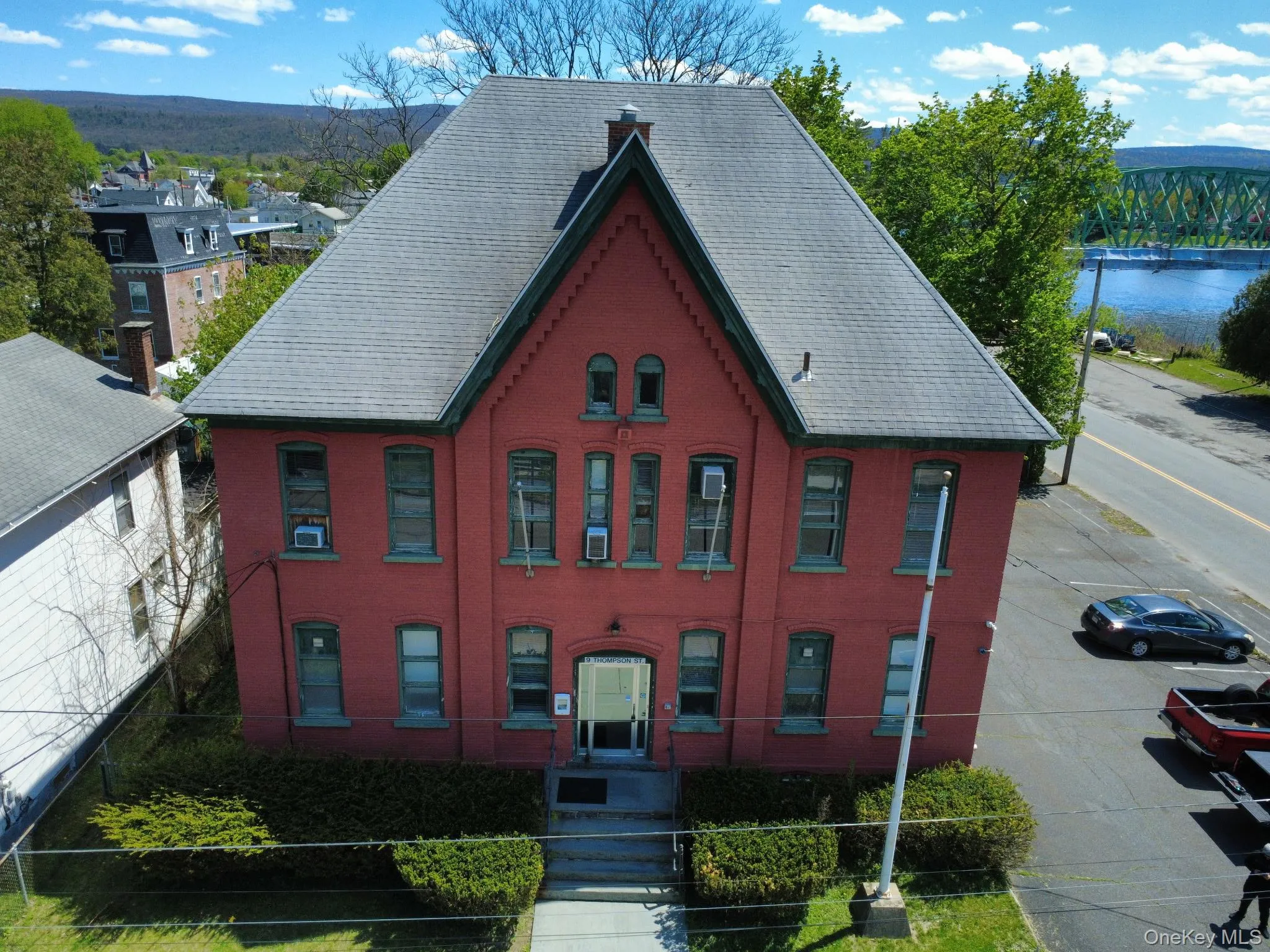 Red brick building with a gray hip roof and green trim Red brick building with a gray hip roof and green trim