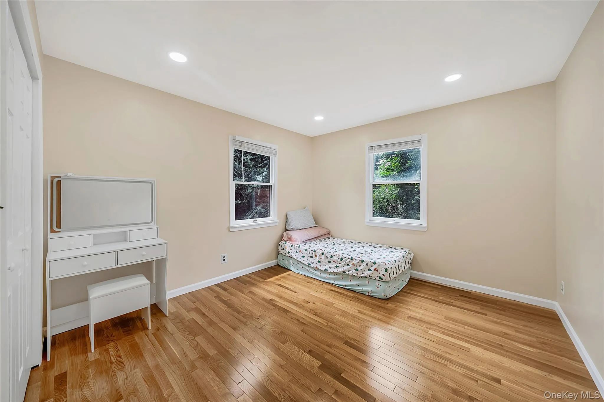 Room featuring wood-finish flooring, recessed lighting, and two windows Room featuring wood-finish flooring, recessed lighting, and two windows