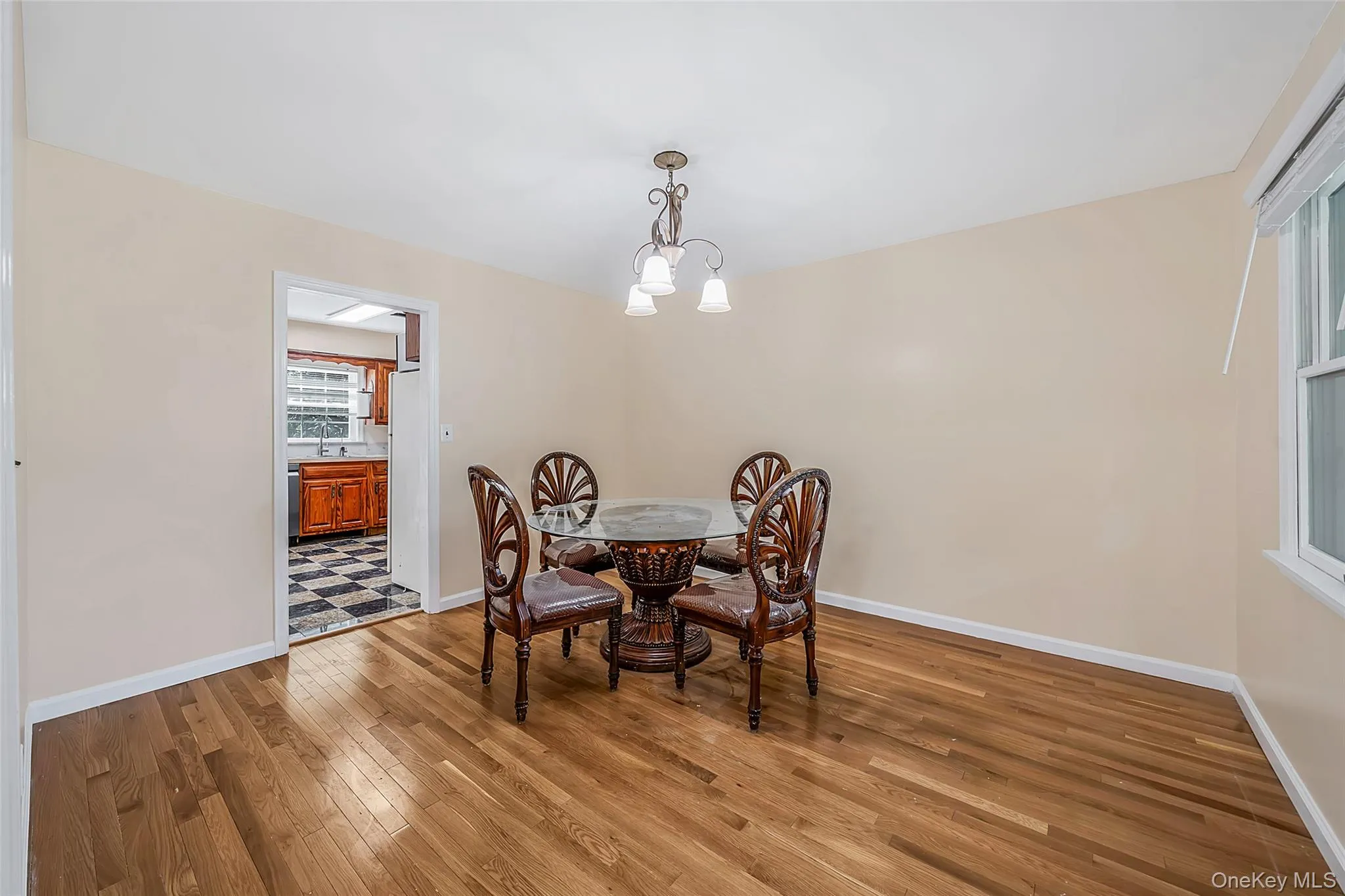 Hardwood flooring throughout this room with a ceiling-mounted light fixture, white trim, and a window with blinds Hardwood flooring throughout this room with a ceiling-mounted light fixture, white trim, and a window with blinds
