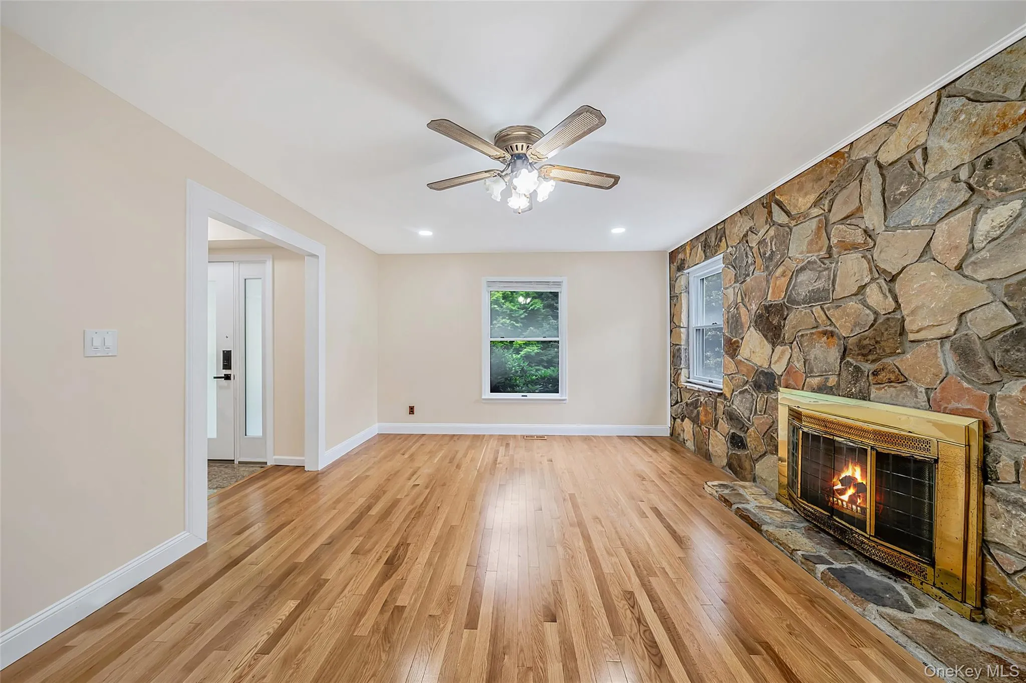 Spacious room featuring a full stone accent wall with an integrated fireplace and brass-toned firebox Spacious room featuring a full stone accent wall with an integrated fireplace and brass-toned firebox