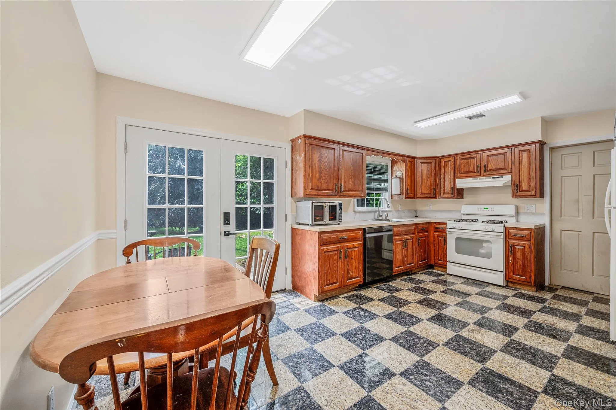 Eat-in kitchen featuring wood cabinetry, white appliances, and a checkered floor pattern Eat-in kitchen featuring wood cabinetry, white appliances, and a checkered floor pattern