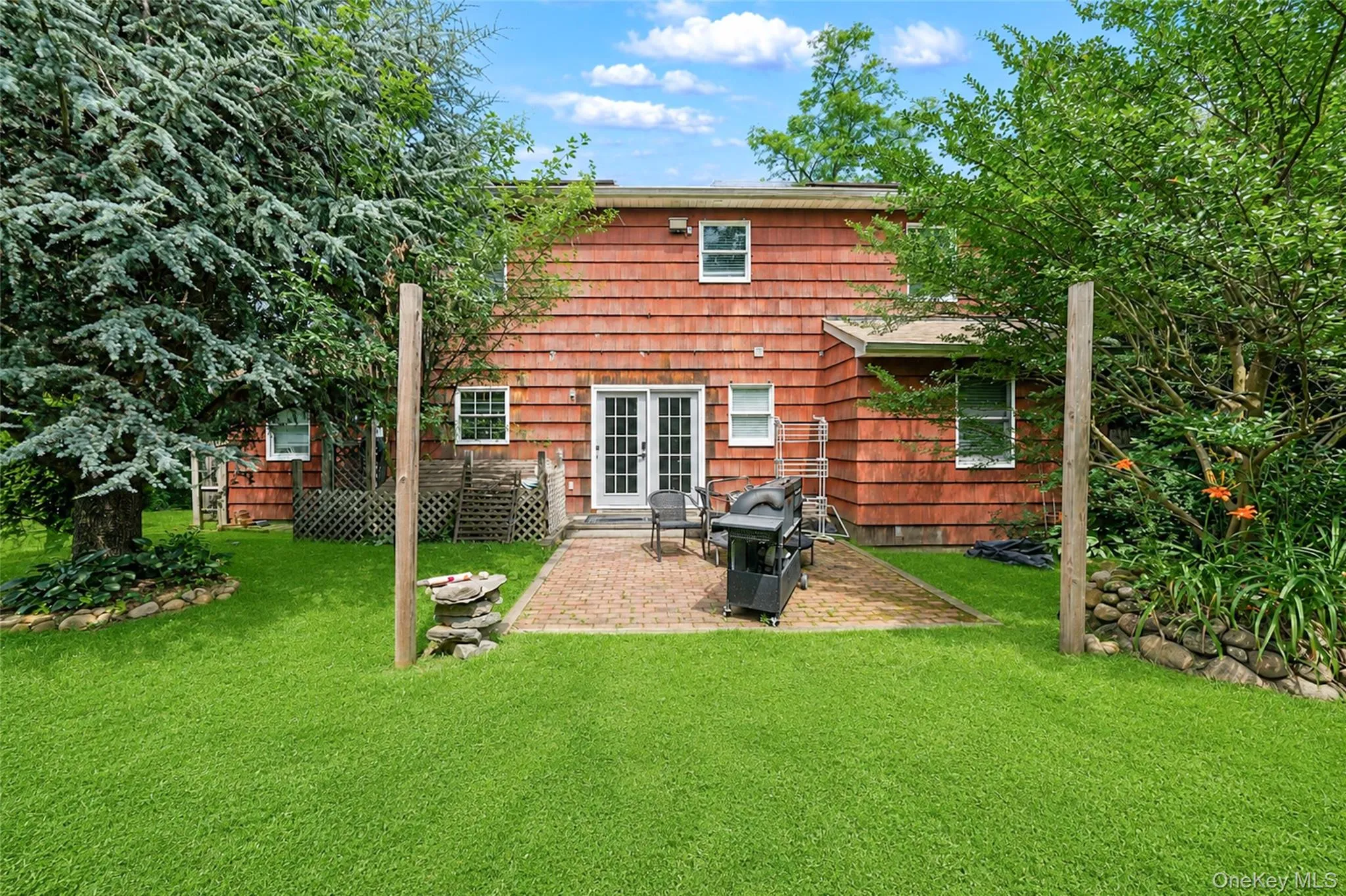 Expansive green lawn with mature trees and a paver patio Expansive green lawn with mature trees and a paver patio