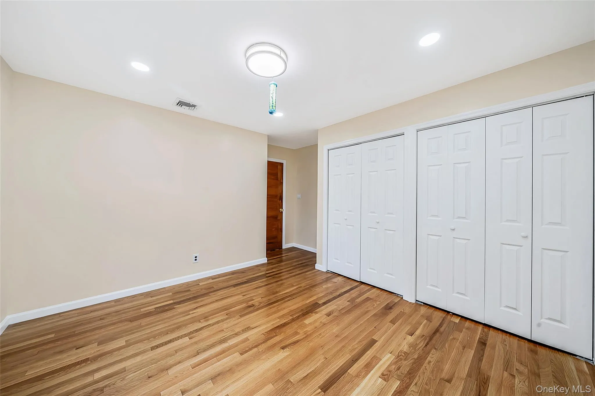 Room featuring wood-finish flooring, light neutral wall paint, and white trim Room featuring wood-finish flooring, light neutral wall paint, and white trim