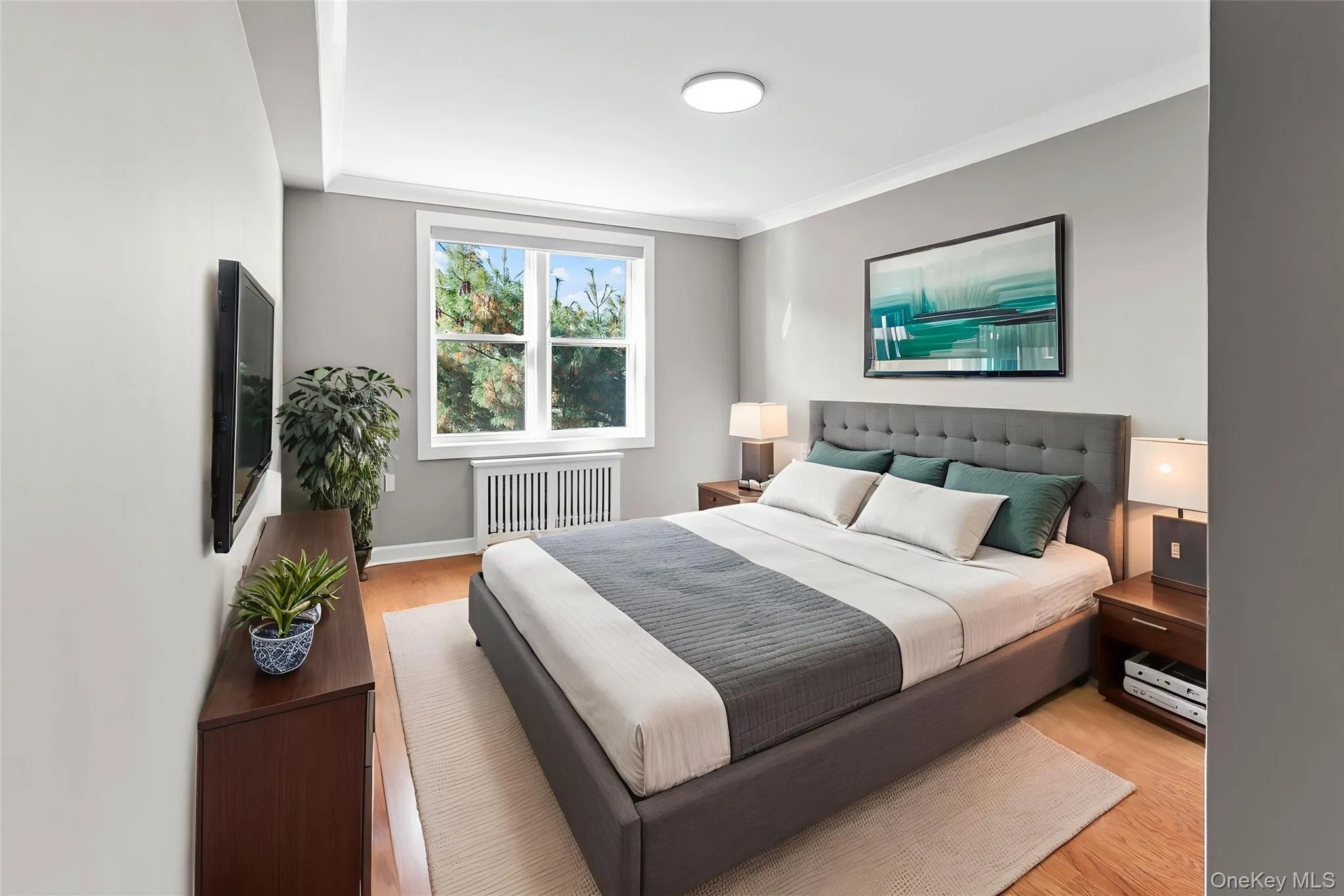 Bedroom with wood finished floors, ornamental molding, and radiator heating unit Bedroom with wood finished floors, ornamental molding, and radiator heating unit
