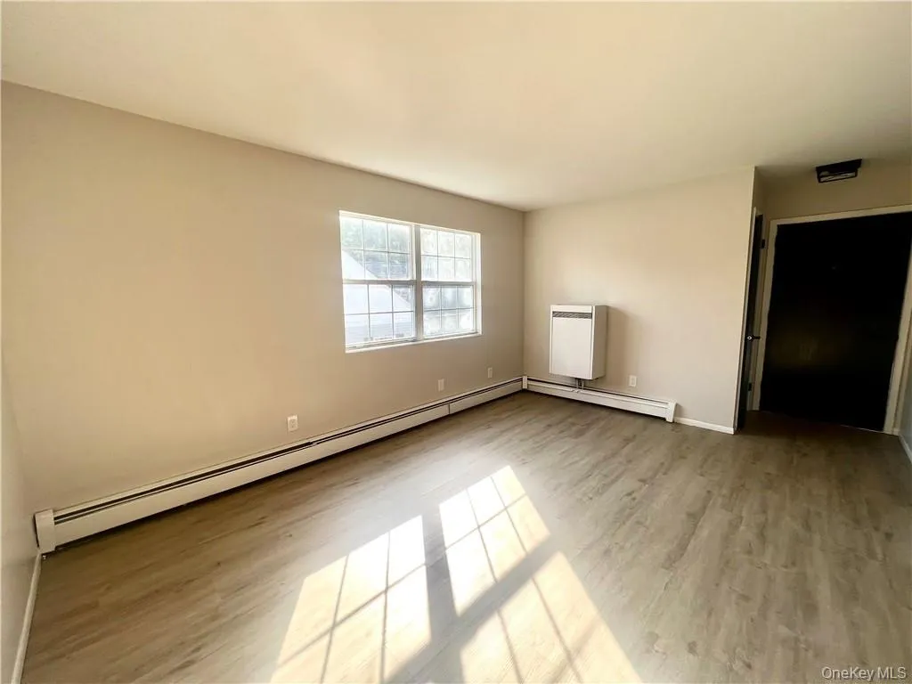 Unfurnished bedroom with light wood-type flooring and baseboard heating Unfurnished bedroom with light wood-type flooring and baseboard heating