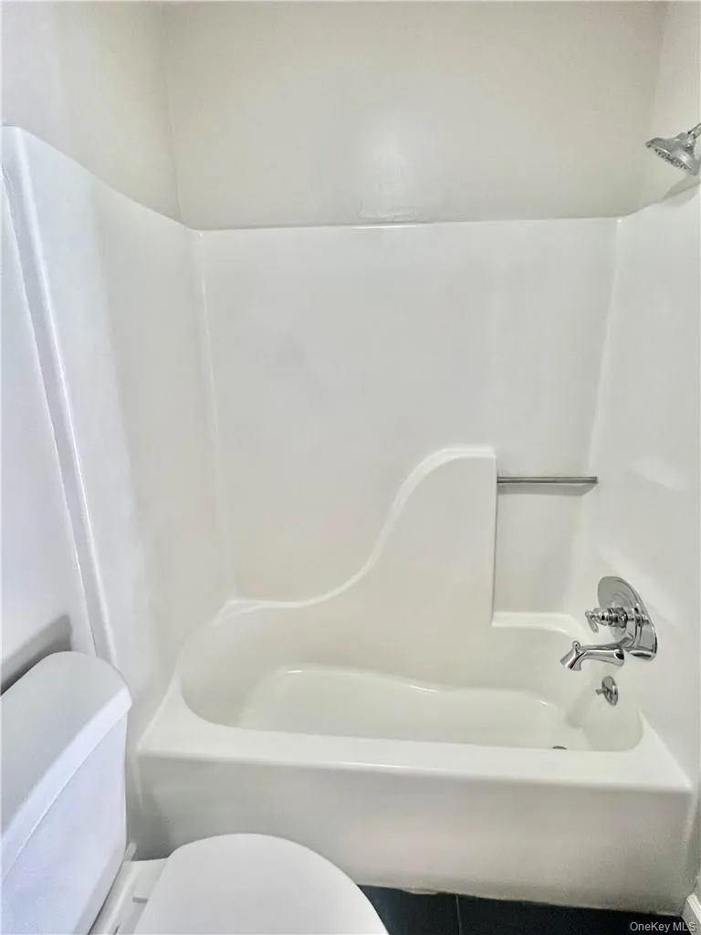 Bathroom featuring shower / bathing tub combination and toilet Bathroom featuring shower / bathing tub combination and toilet