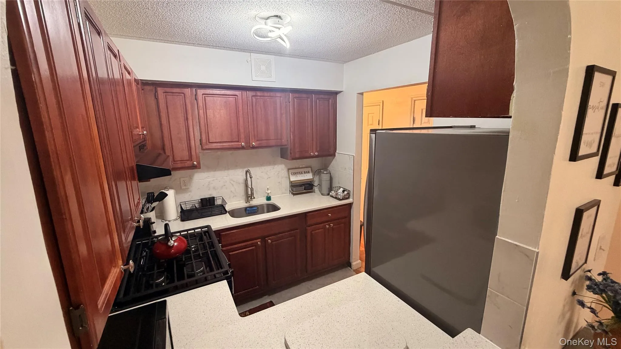 Kitchen featuring wood cabinetry, white stone countertops, and a tile backsplash Kitchen featuring wood cabinetry, white stone countertops, and a tile backsplash