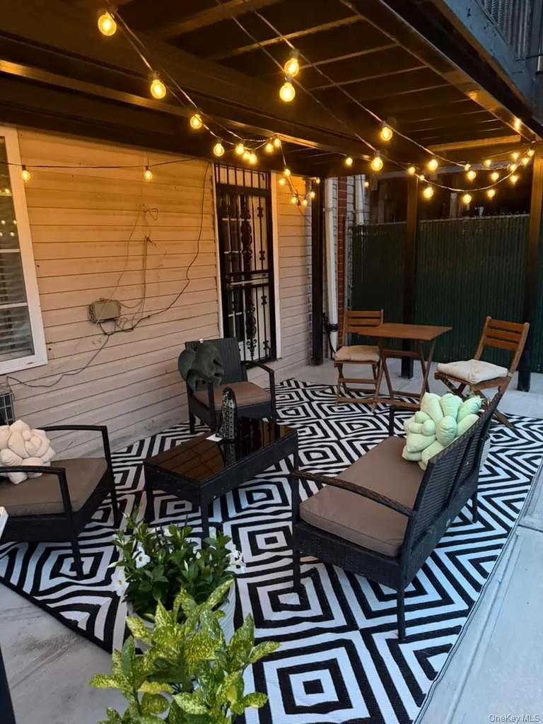 Covered outdoor patio area featuring string lighting, a geometric pattern outdoor rug, and a privacy screen Covered outdoor patio area featuring string lighting, a geometric pattern outdoor rug, and a privacy screen