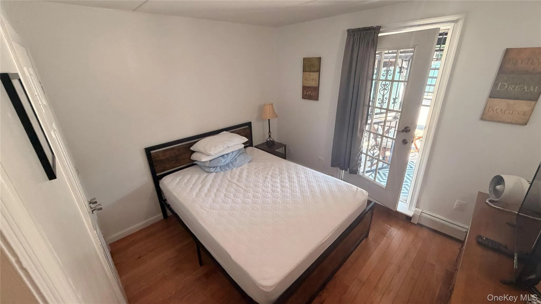 Hardwood-finish flooring, white walls, and a full-light exterior door with decorative security bars Hardwood-finish flooring, white walls, and a full-light exterior door with decorative security bars
