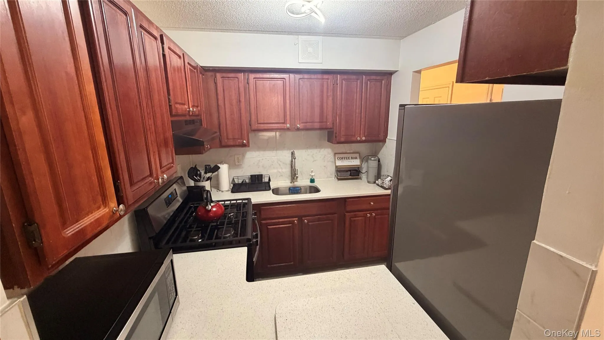 Kitchen featuring wood-finish cabinetry, white countertops, and a white tile backsplash Kitchen featuring wood-finish cabinetry, white countertops, and a white tile backsplash