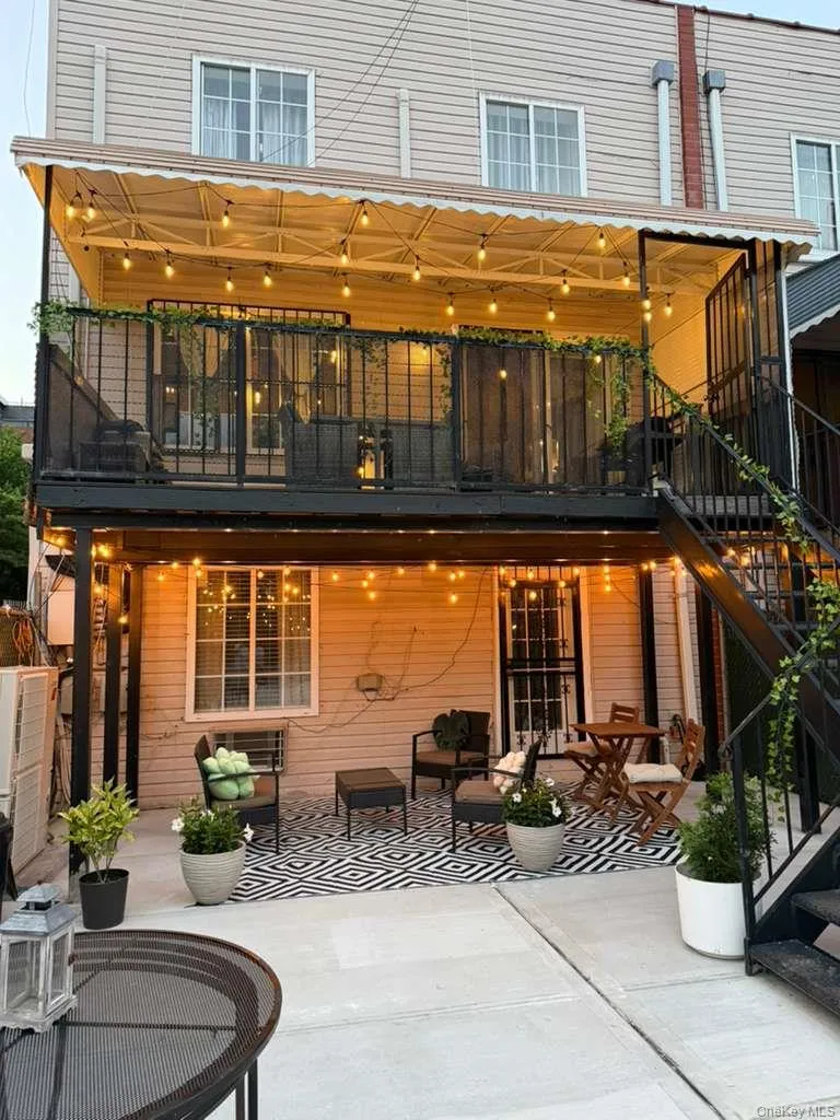 Multi-level outdoor space featuring a covered balcony, a ground-floor patio with a concrete surface, and external metal staircases Multi-level outdoor space featuring a covered balcony, a ground-floor patio with a concrete surface, and external metal staircases