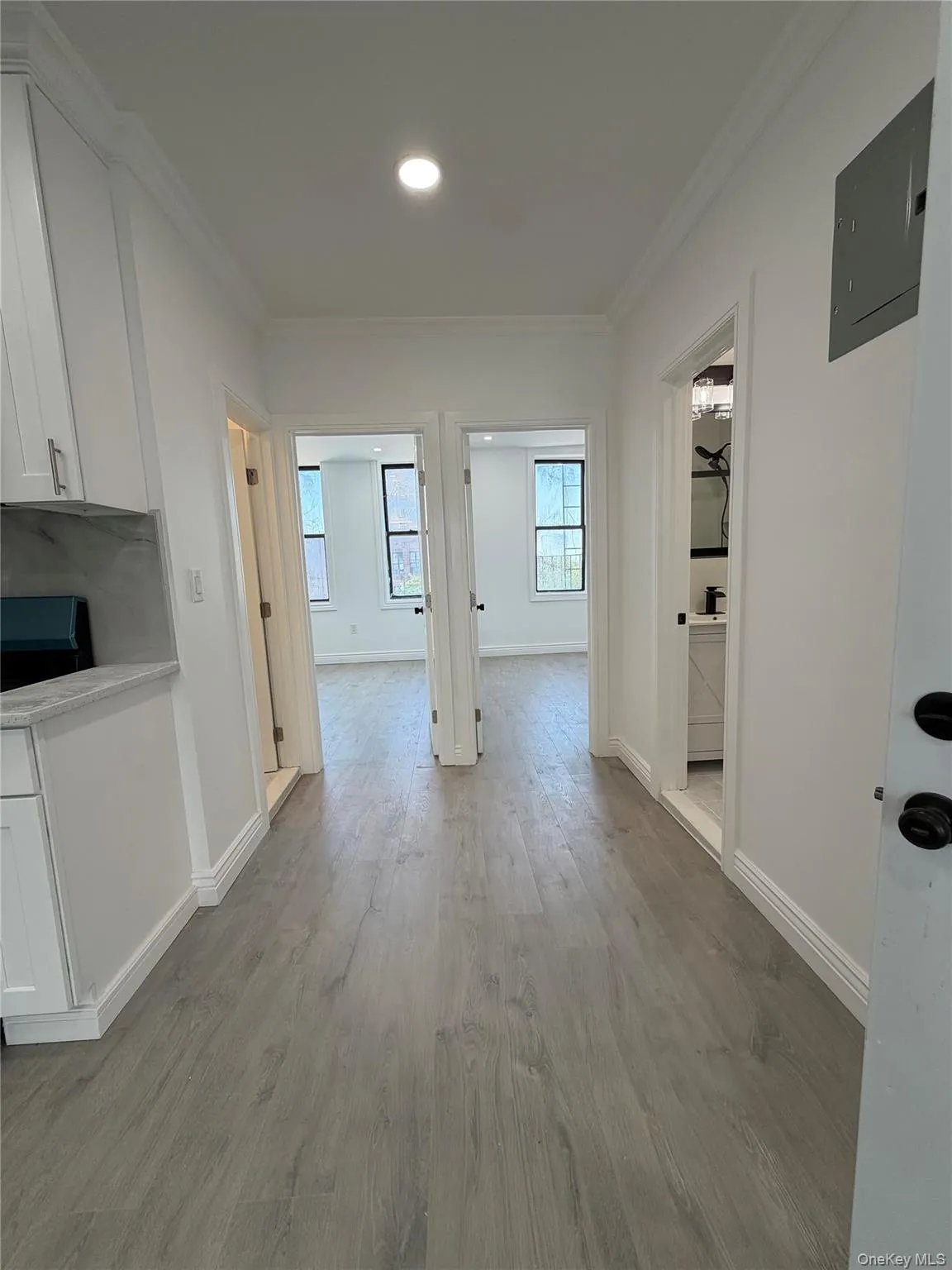 Hallway featuring wood-finish flooring, recessed lighting, white trim, and white walls Hallway featuring wood-finish flooring, recessed lighting, white trim, and white walls
