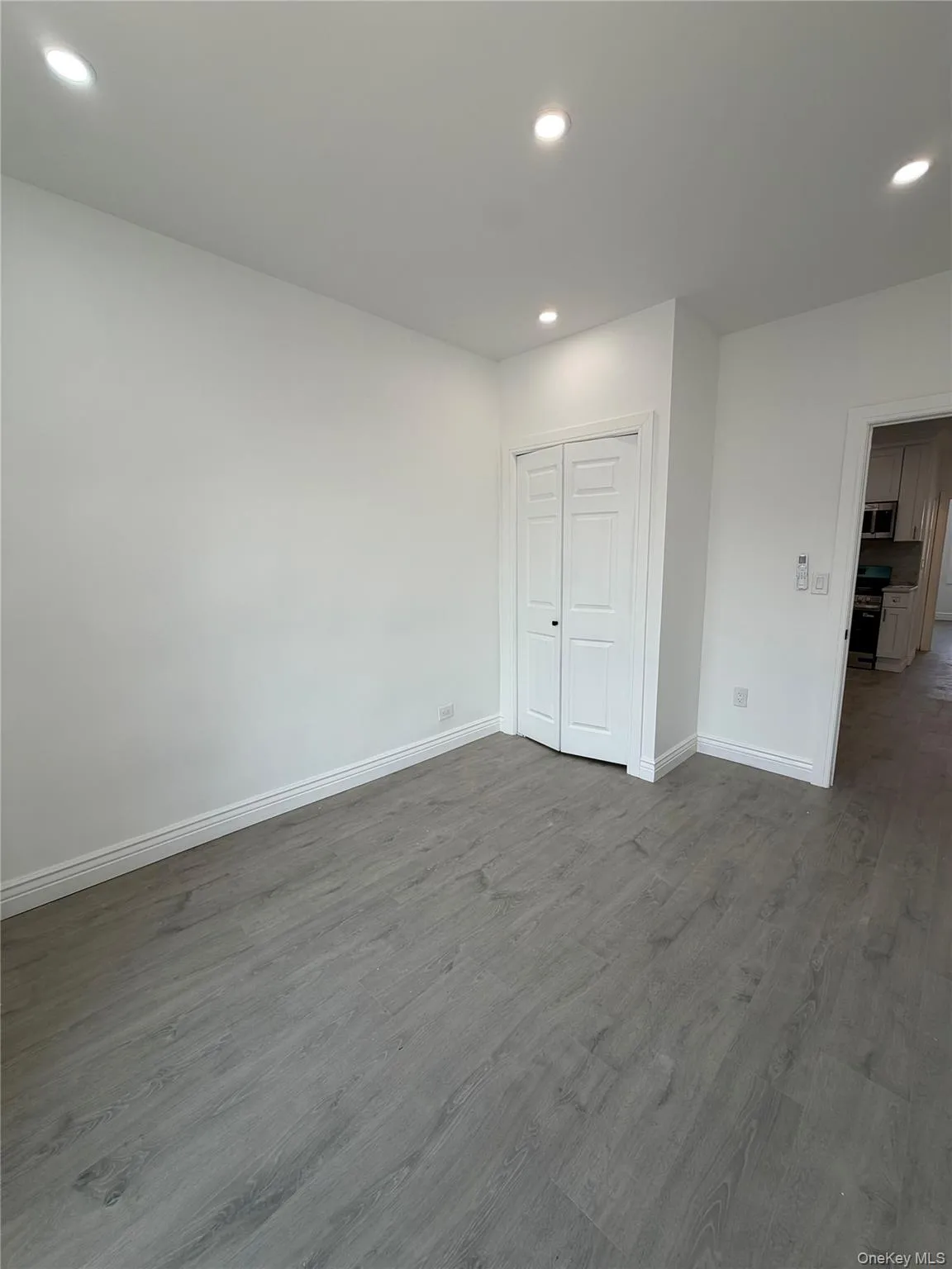 spacious room wood-finish flooring, recessed lighting, white walls, and white baseboards spacious room wood-finish flooring, recessed lighting, white walls, and white baseboards