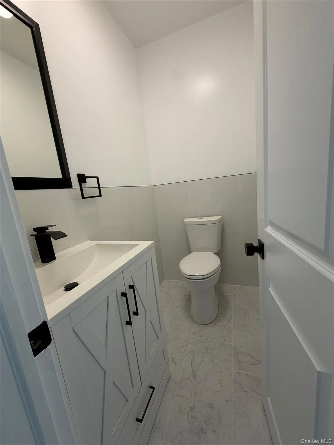 Modern bathroom featuring a white vanity with black hardware, a rectangular basin, and a black faucet Modern bathroom featuring a white vanity with black hardware, a rectangular basin, and a black faucet