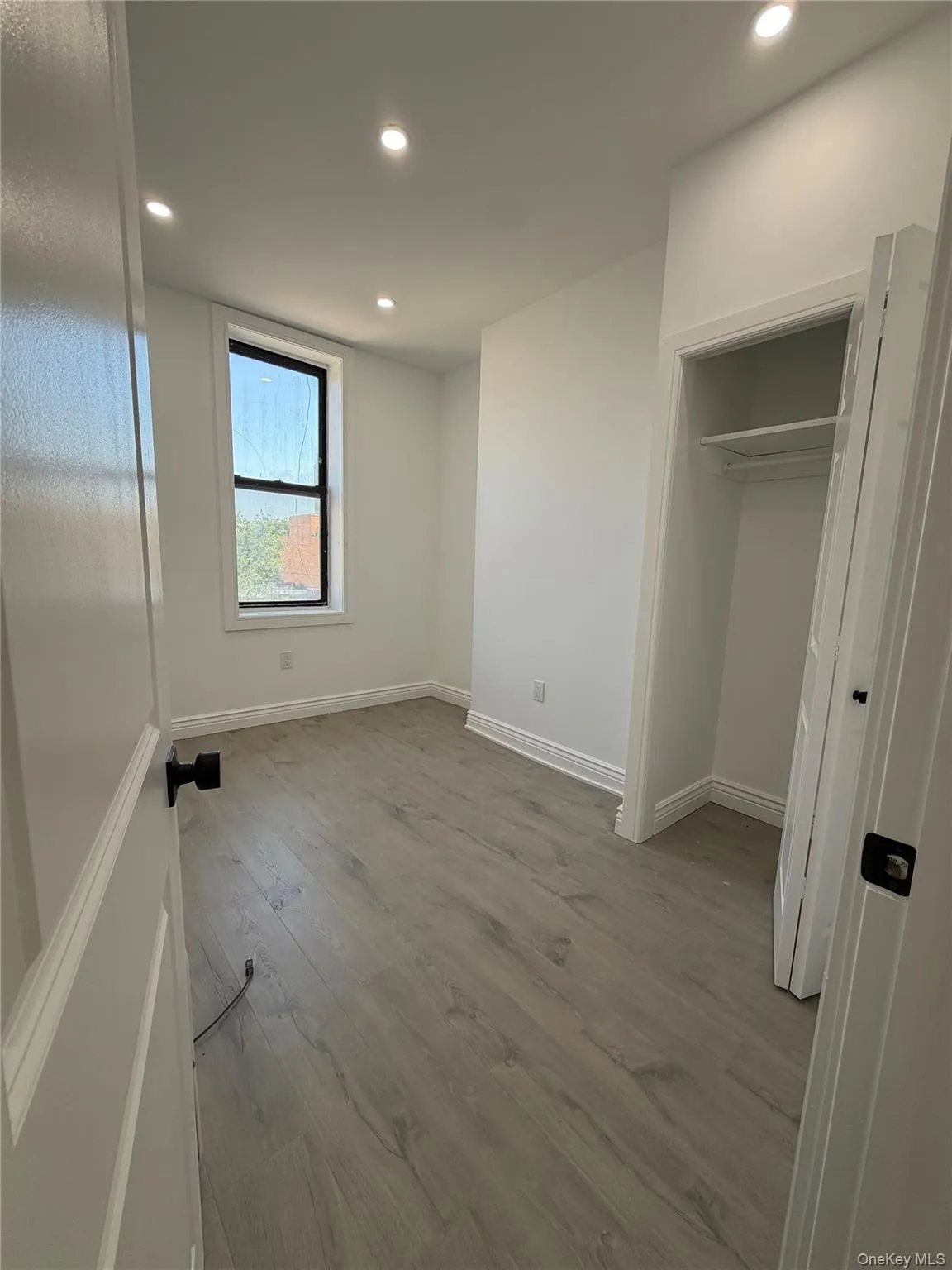 Bright interior space featuring wood-finish flooring, white baseboards, and clean white walls Bright interior space featuring wood-finish flooring, white baseboards, and clean white walls